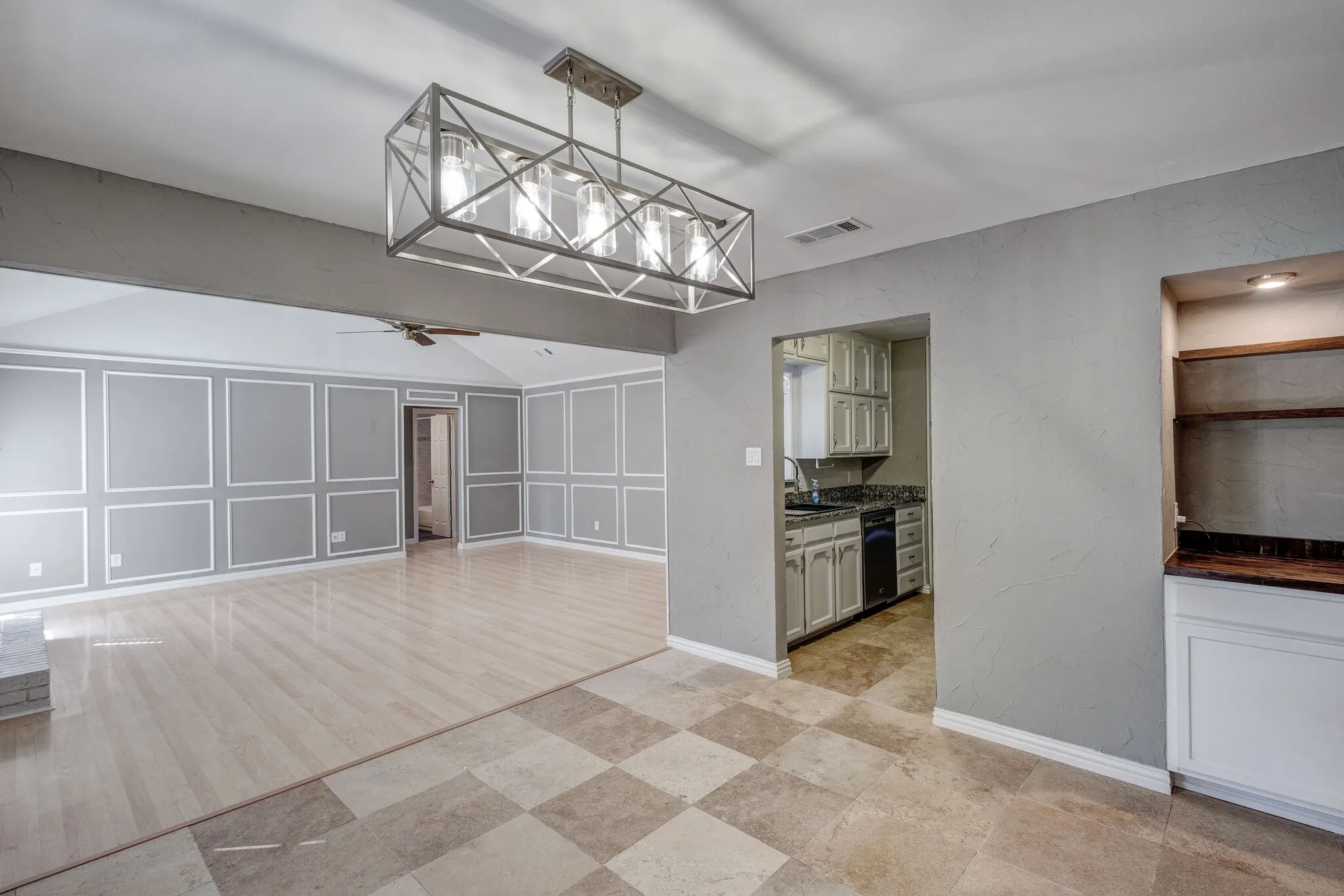 Open-concept living area with vaulted ceiling, wood-finish flooring, and decorative wall paneling