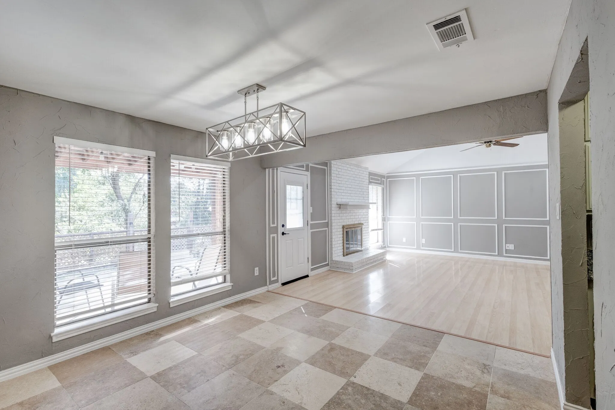 Checkerboard tile flooring, contemporary chandelier, recessed lighting, white brick fireplace with mantel, decorative wall molding
