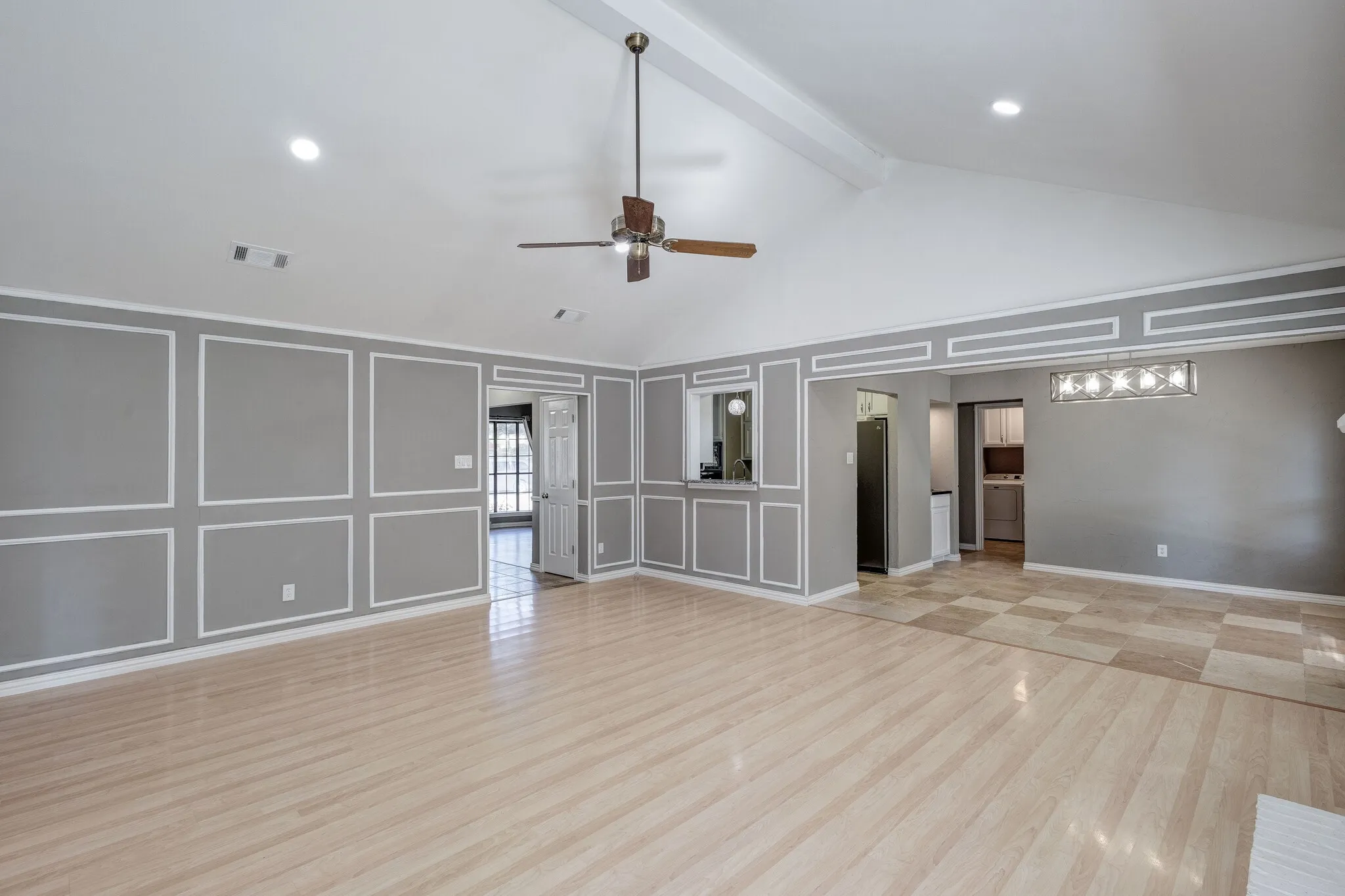 Vaulted ceiling with exposed beam, wood-finish flooring, decorative wall molding, recessed lighting, and a ceiling fan