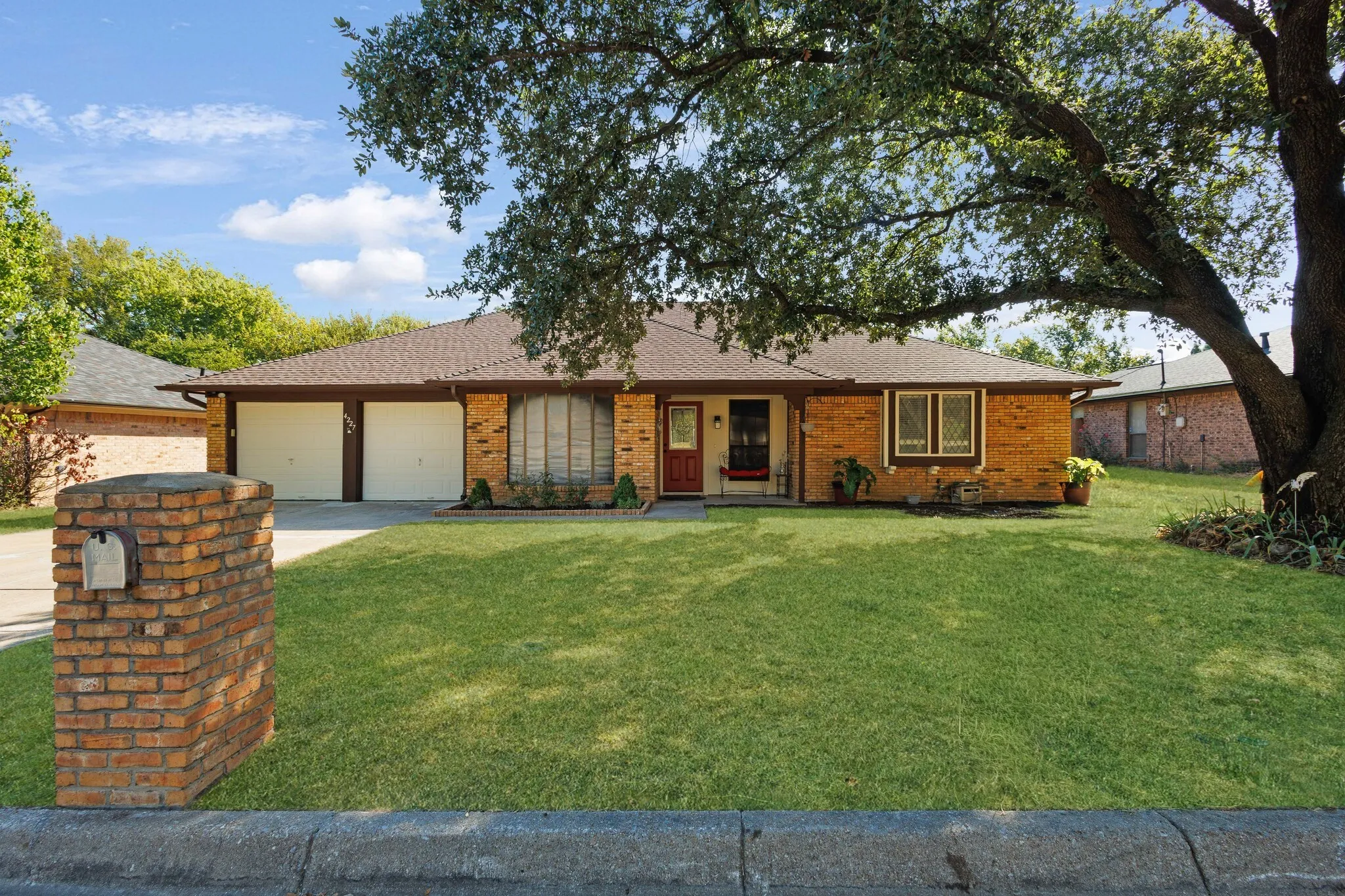 Brick exterior with a prominent mature tree and a well-maintained lawn