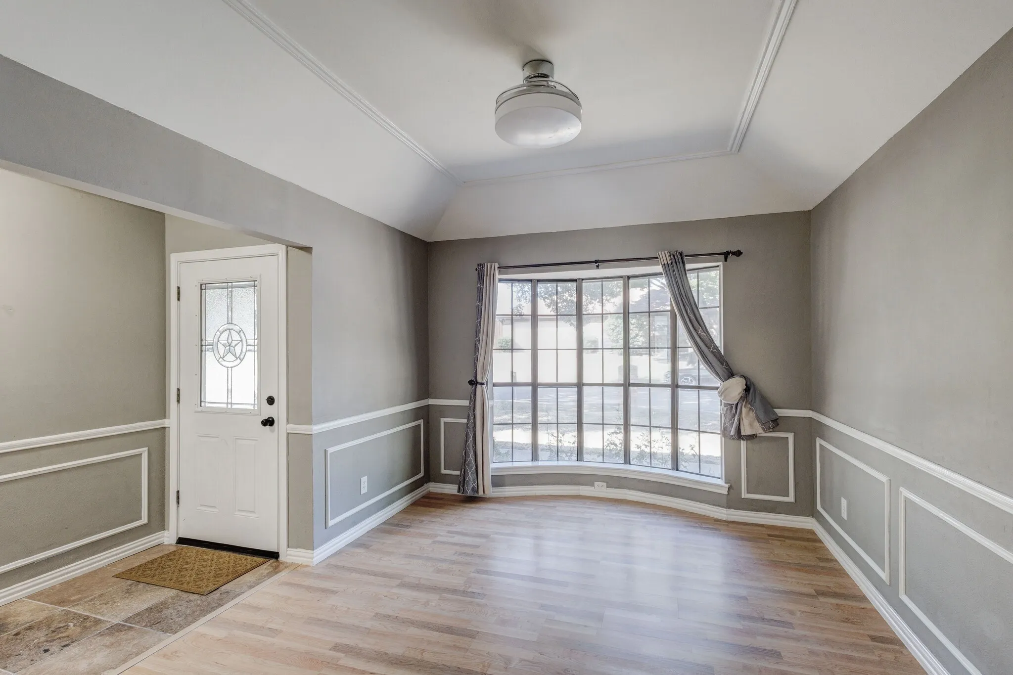 Entryway with decorative glass panel door, wood-finish flooring, and wainscoting