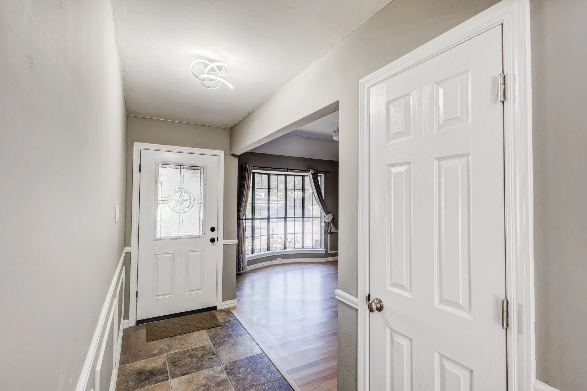 Entryway featuring decorative wainscoting, a modern ceiling fixture, and tile flooring