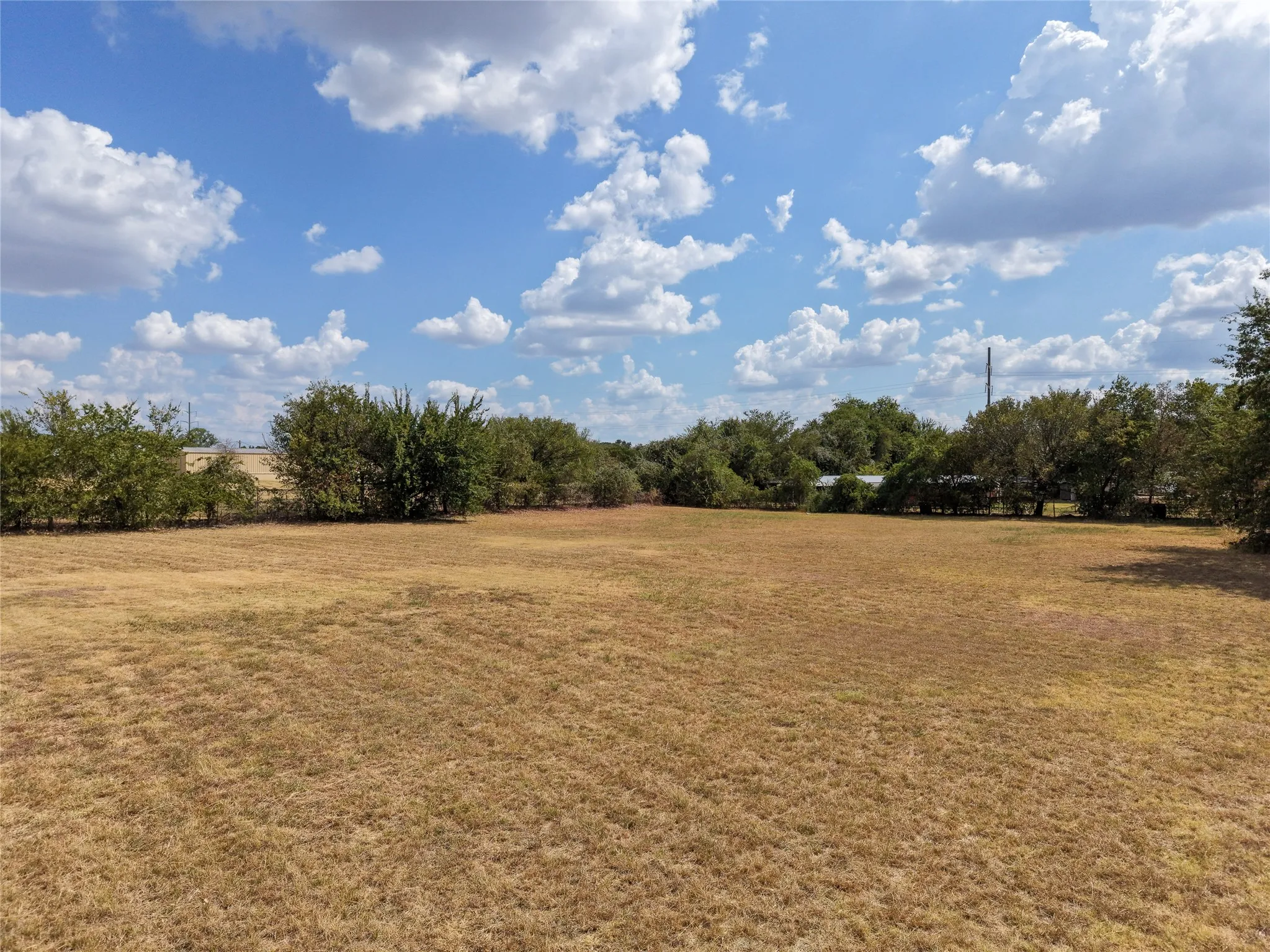 Expansive land parcel featuring natural terrain and perimeter trees