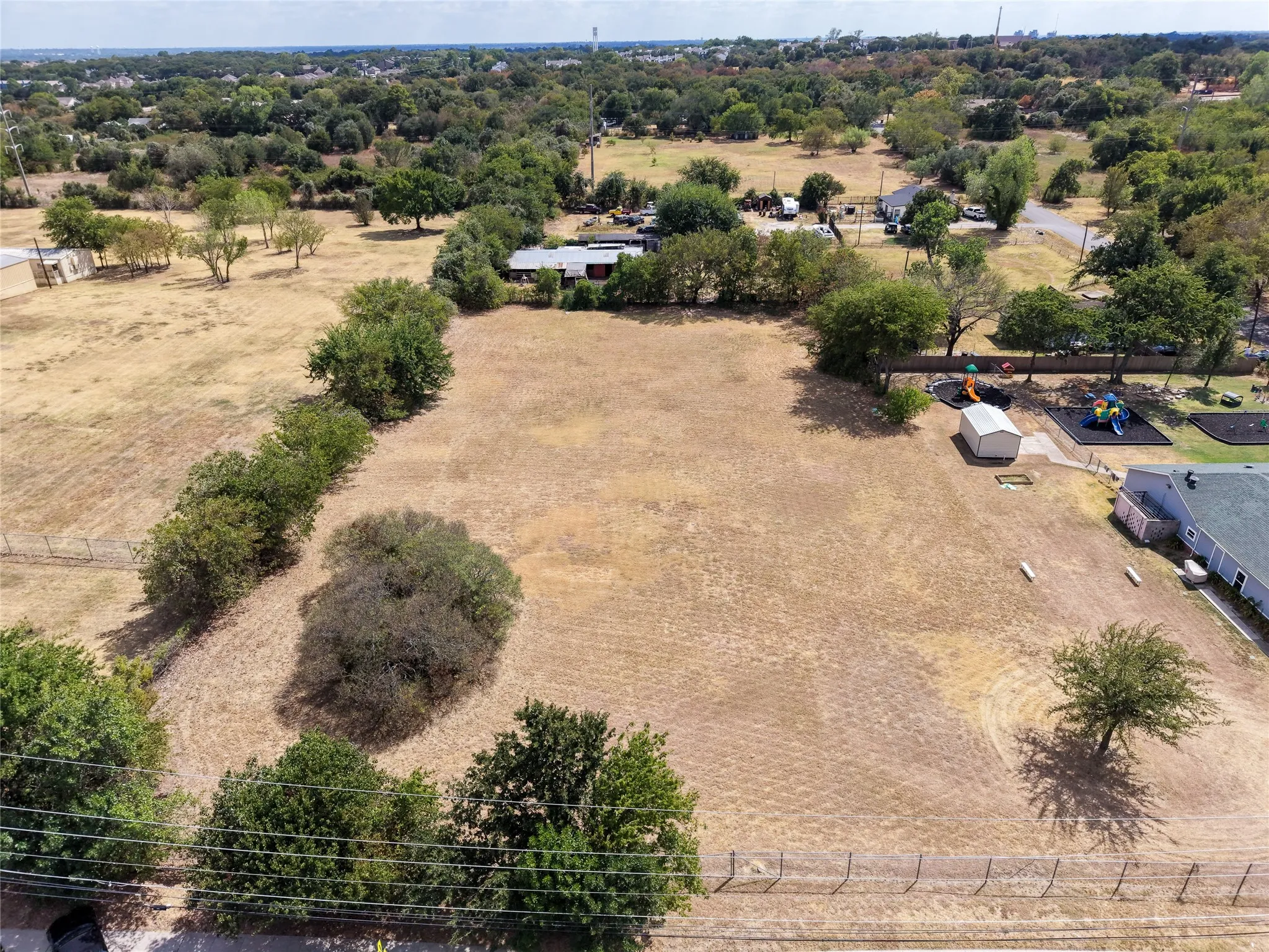 Expansive undeveloped lot with existing perimeter fencing and mature trees