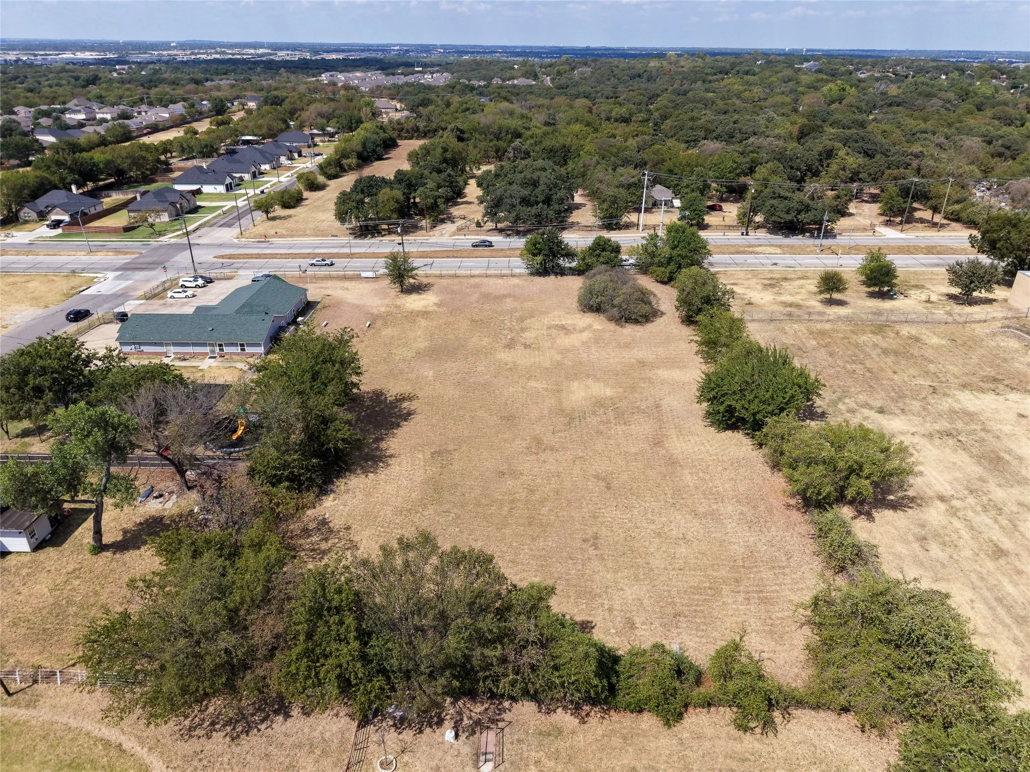 Expansive open land area with mature trees bordering the perimeter
