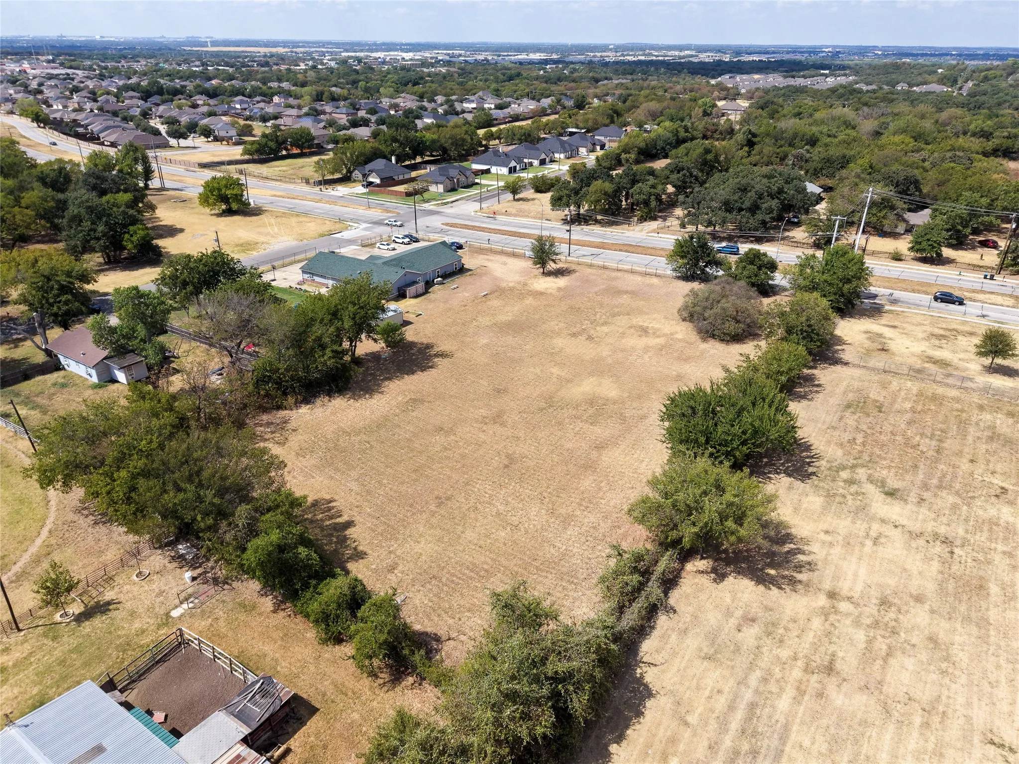 Expansive undeveloped land featuring mature trees and a perimeter fence