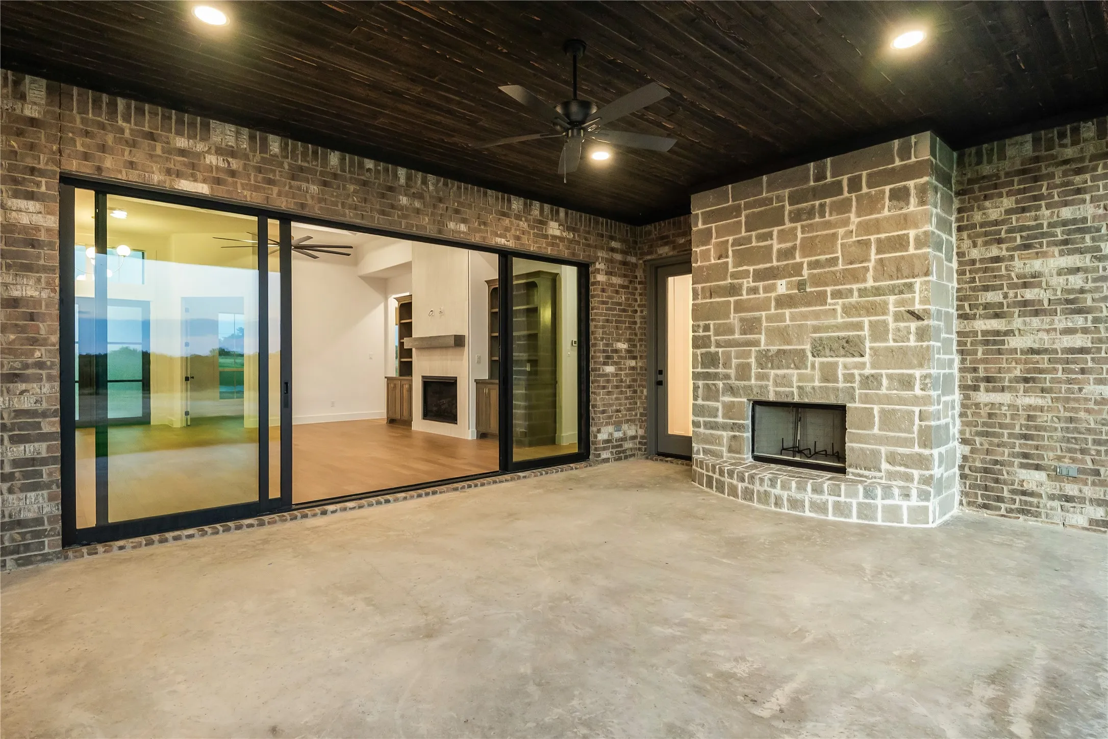 Outdoor patio featuring a stone-clad fireplace, dark wood-finish ceiling, and recessed lighting