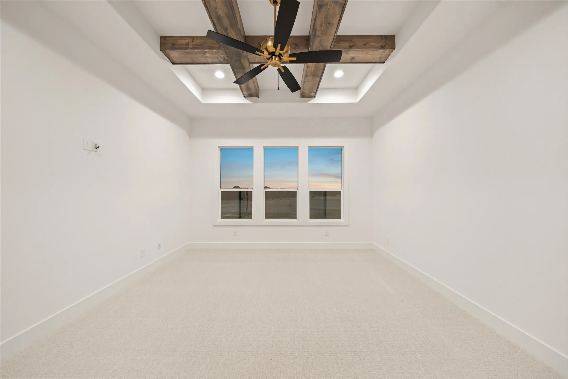 Coffered ceiling with exposed wood beams and recessed lighting, gold-finish ceiling fan, three pane windows, and light-tone carpeting