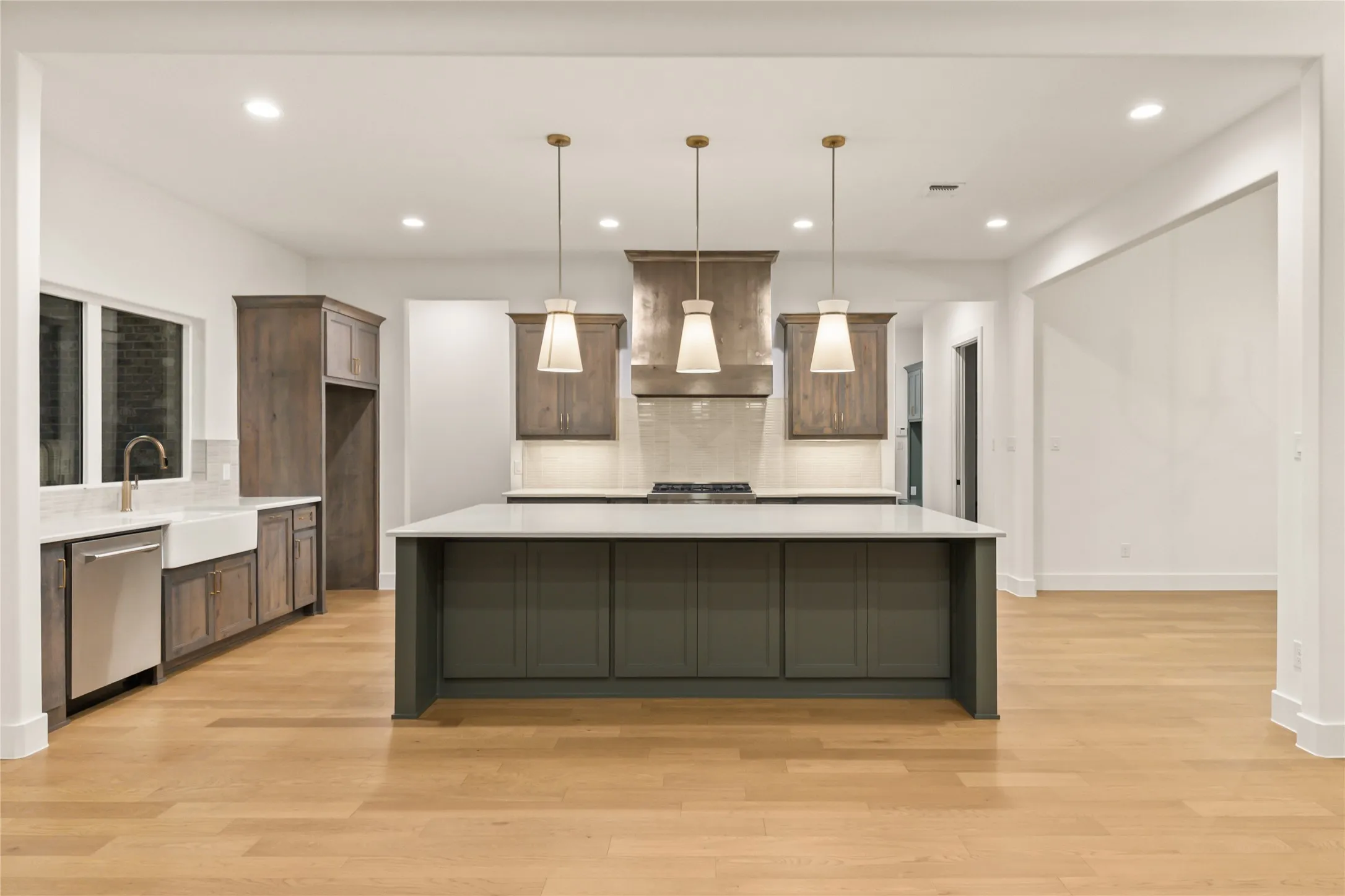 Spacious kitchen featuring a large island, wood-finish flooring, recessed lighting, and pendant lights