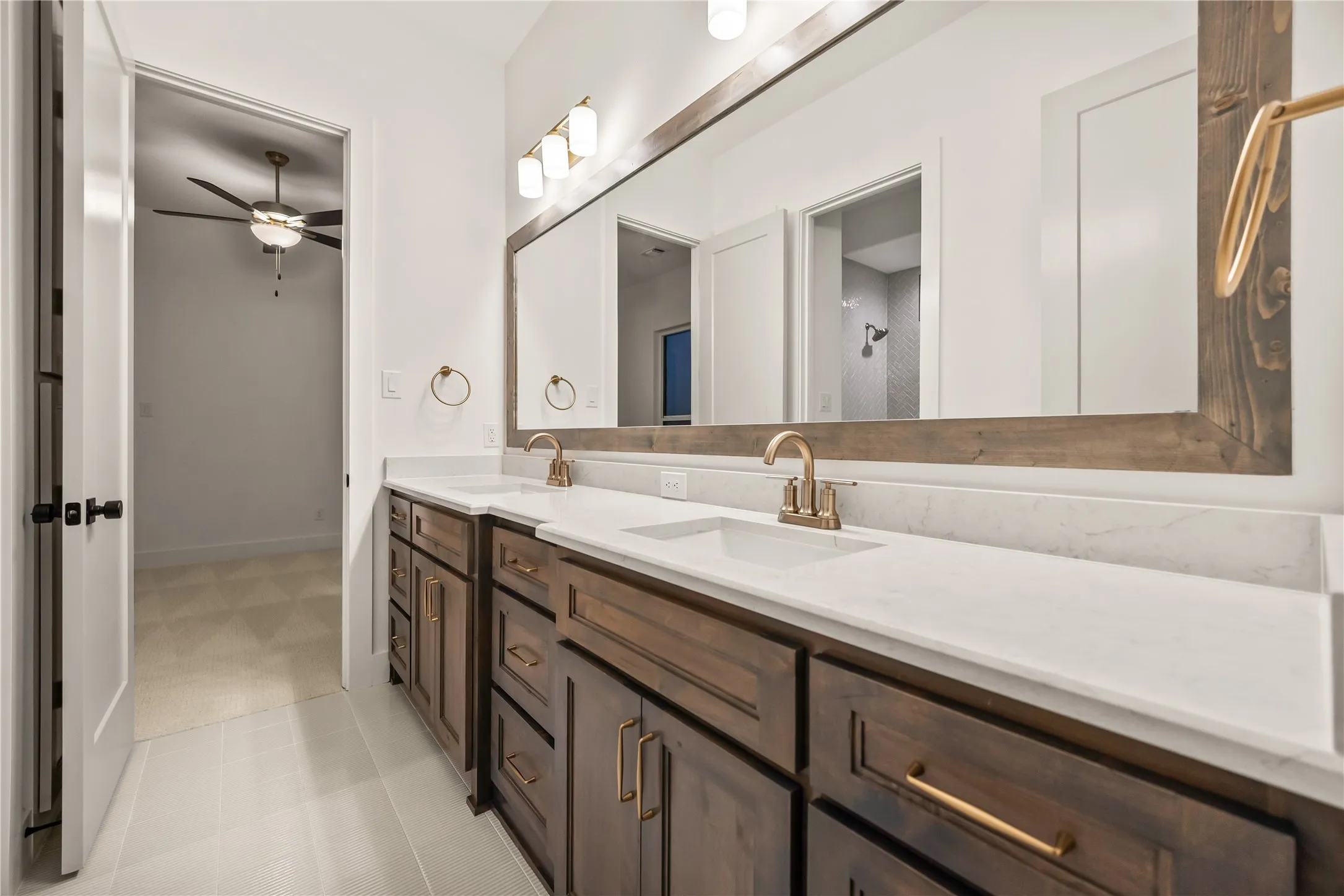 Dual vanity with integrated sinks and white countertops, accented by brass-finish fixtures