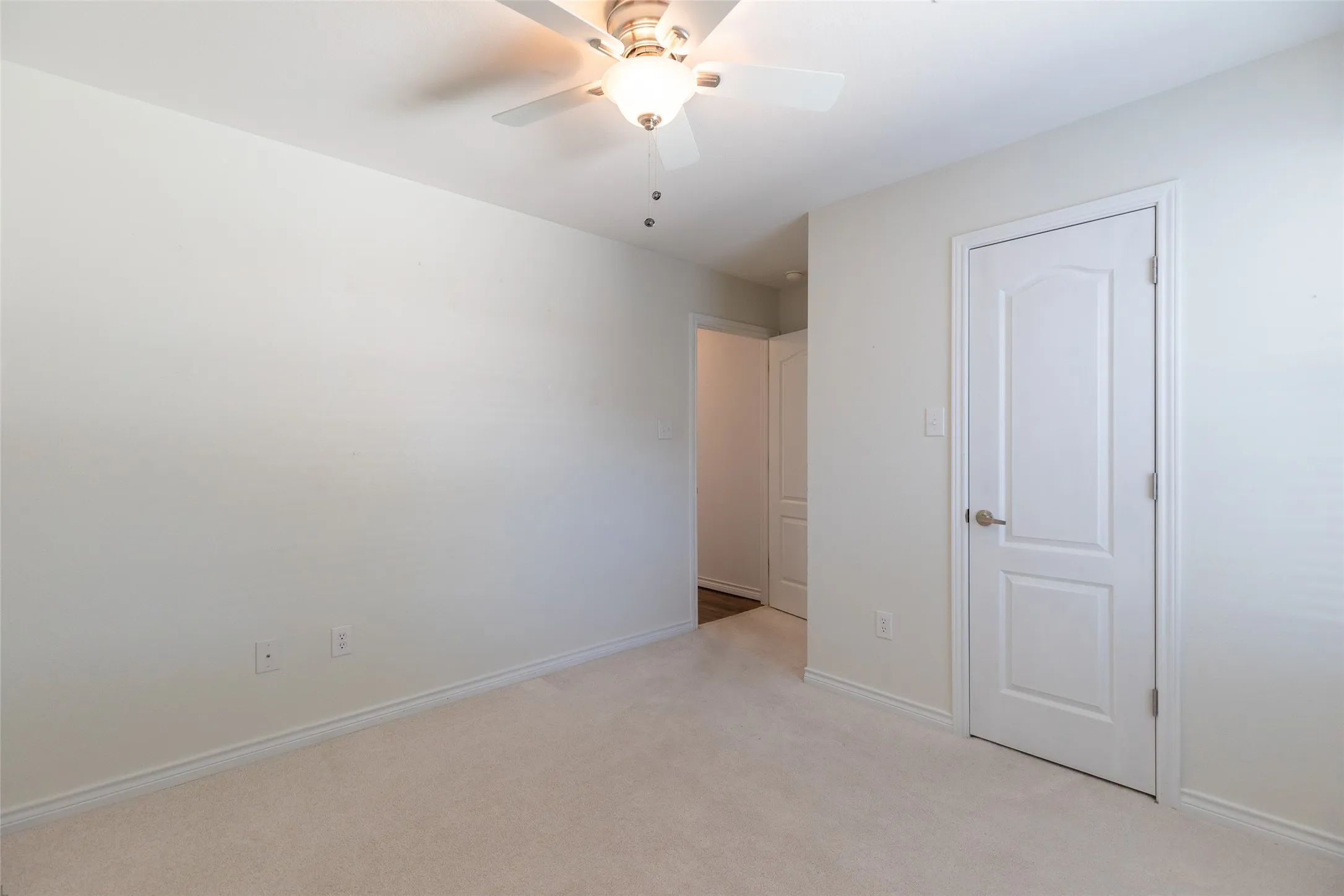 Light-colored carpeting, white interior doors, and a ceiling fan with integrated lighting