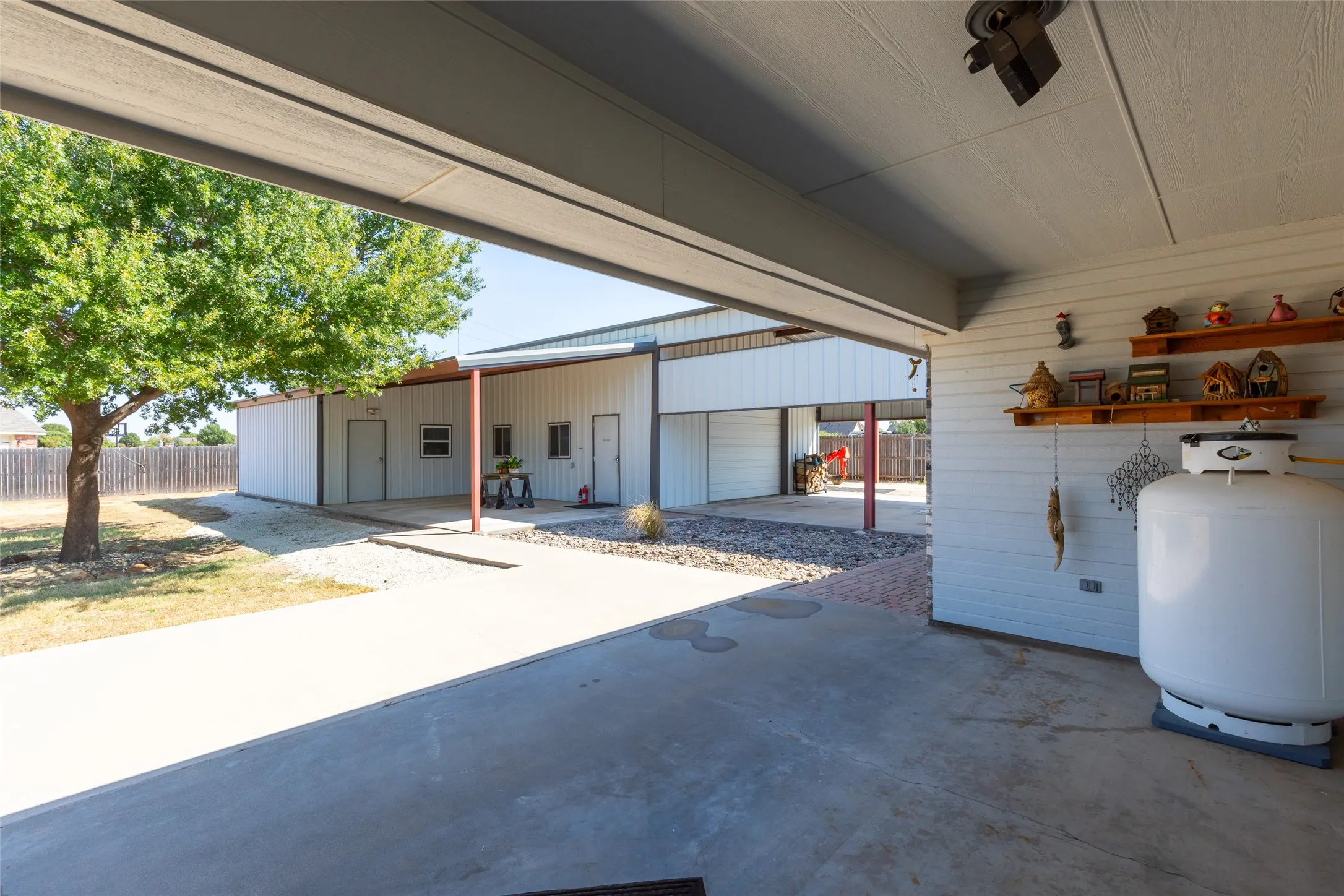 Covered concrete patio with a paneled ceiling, leading to a concrete driveway
