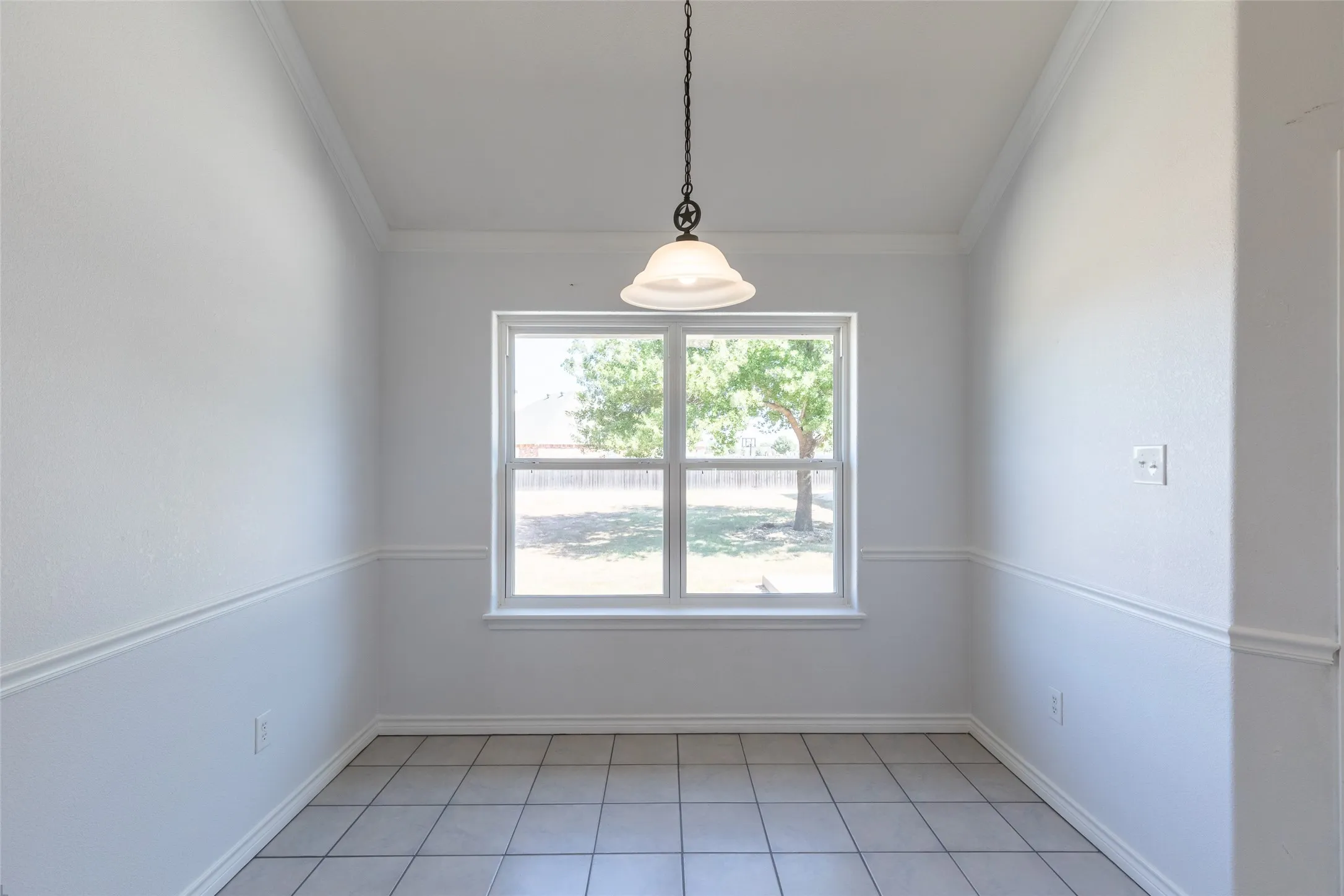 Tile flooring, chair rail molding, crown molding, and a window with outdoor scenery