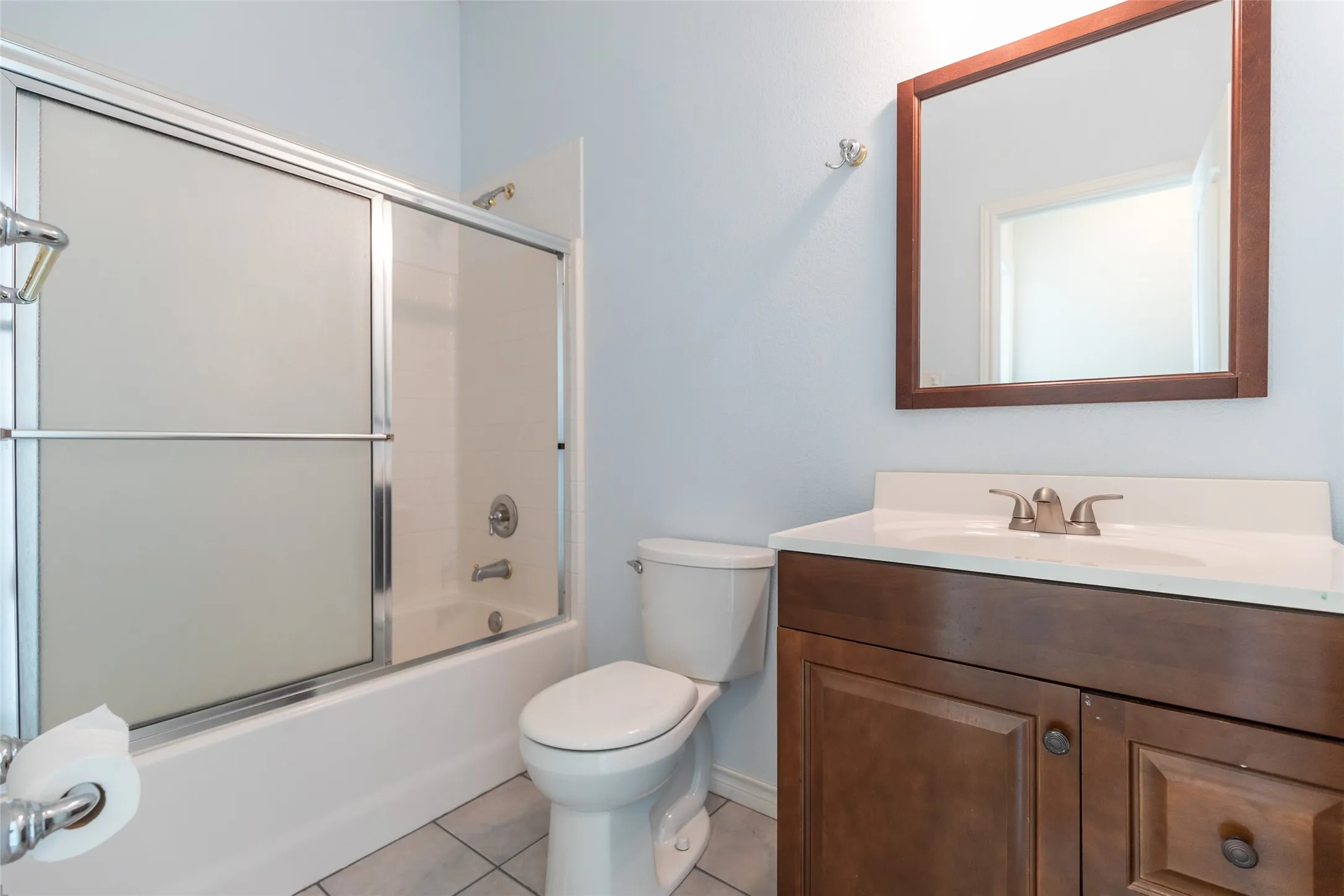 Wood-finish vanity with a white countertop and brushed nickel faucet