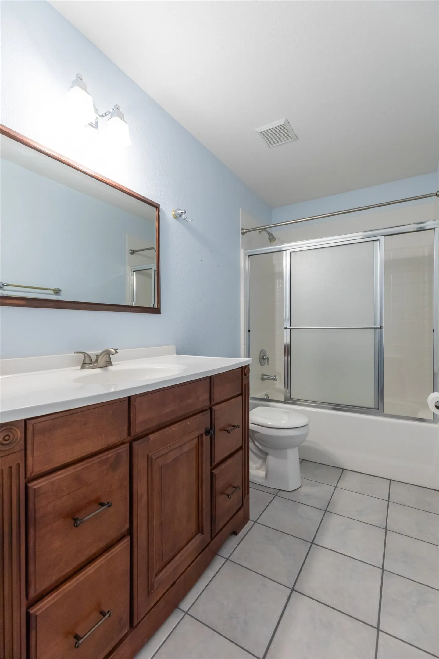 Wood-finish vanity with white countertop, integrated sink, and brushed nickel faucet