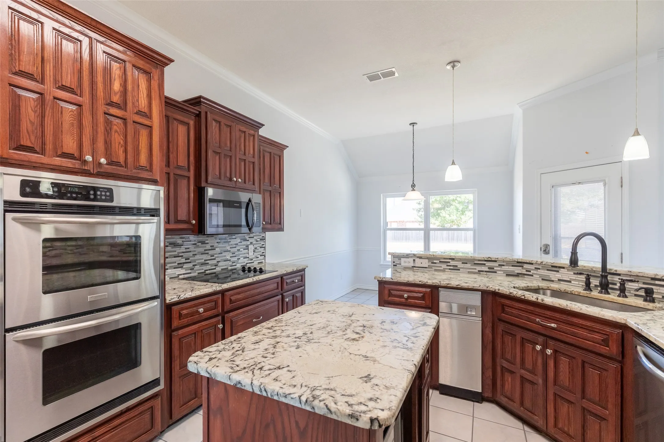 Kitchen featuring abundant wood cabinetry, stainless steel double ovens, stainless steel microwave, stone countertops, and tile backsplash
