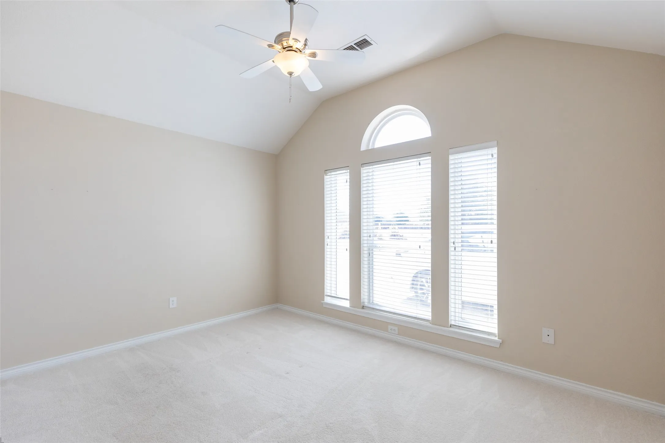 Vaulted ceiling with a ceiling fan, arched transom window, and three vertical windows with blinds