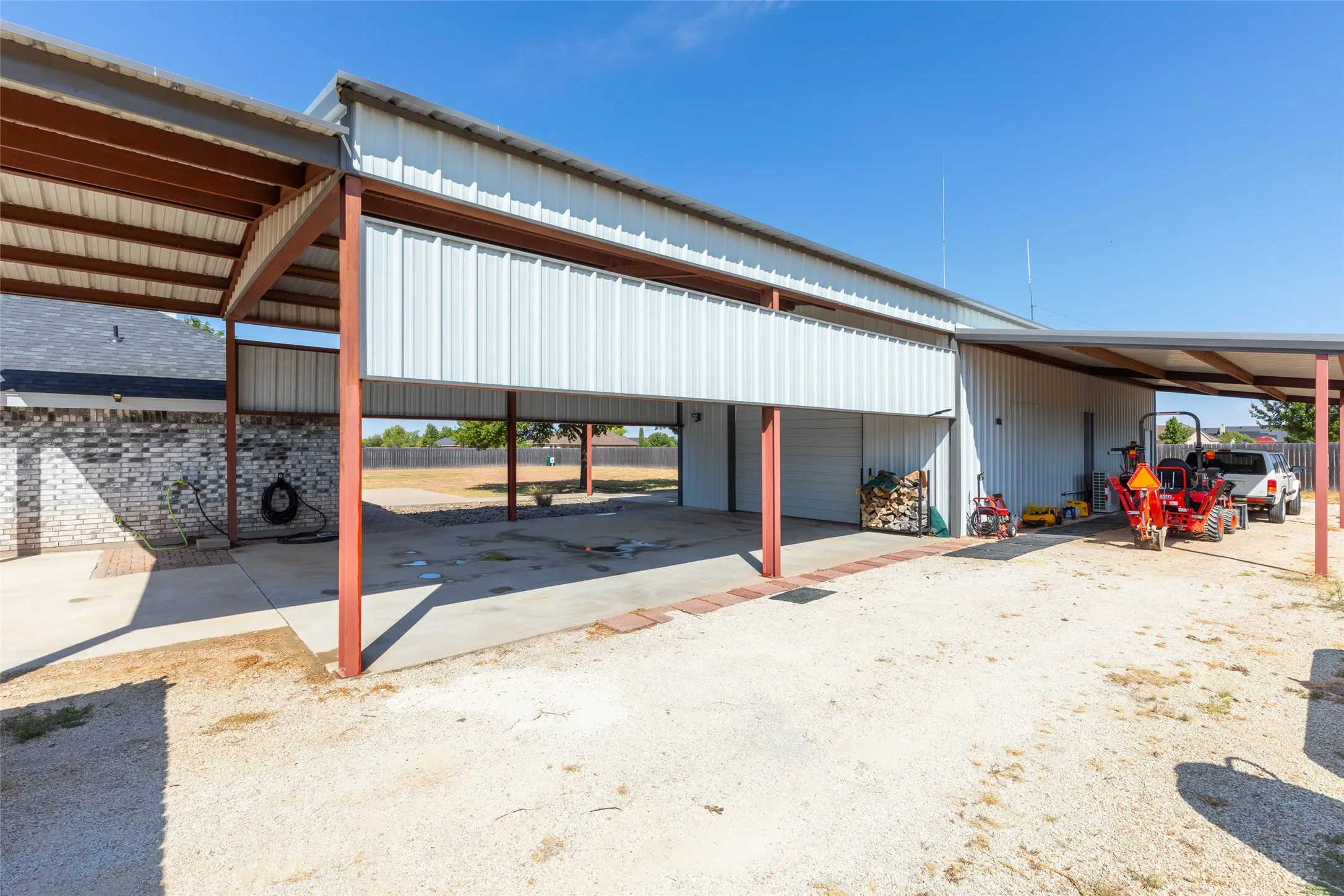 Metal-sided building featuring multiple covered bays, concrete flooring, and an additional attached covered parking structure