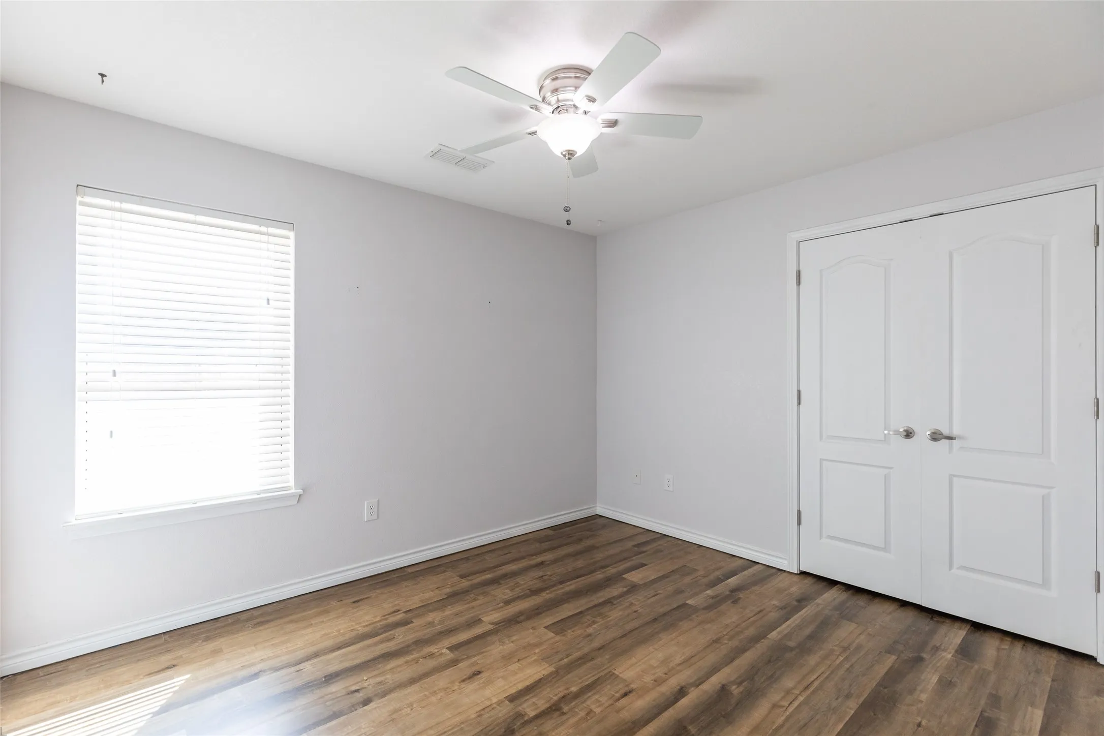 Recessed lighting, wood-finish flooring, ceiling fan with integrated lighting, window with blinds, and double panel doors