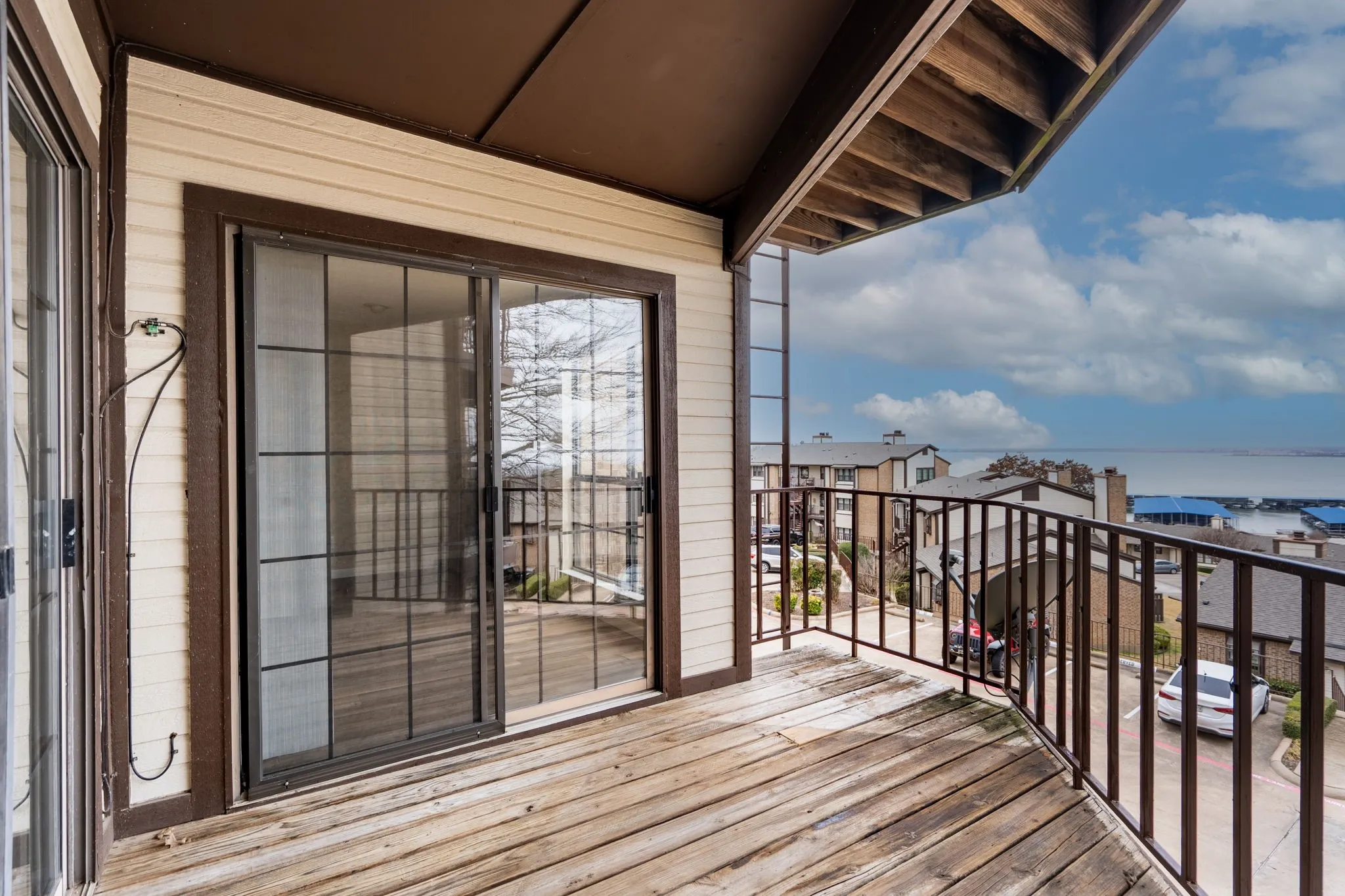 Private balcony featuring wood-finish decking, dark metal railing, and a sliding glass door