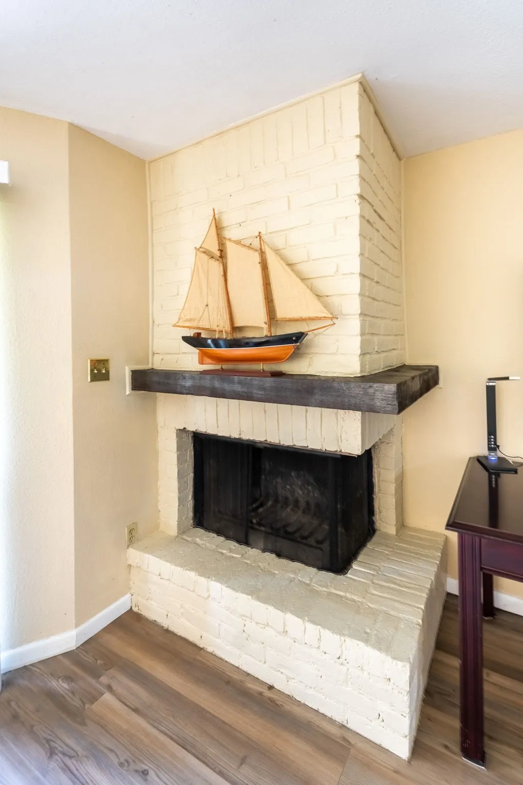 Corner brick fireplace with a wood mantel and wood-finish flooring