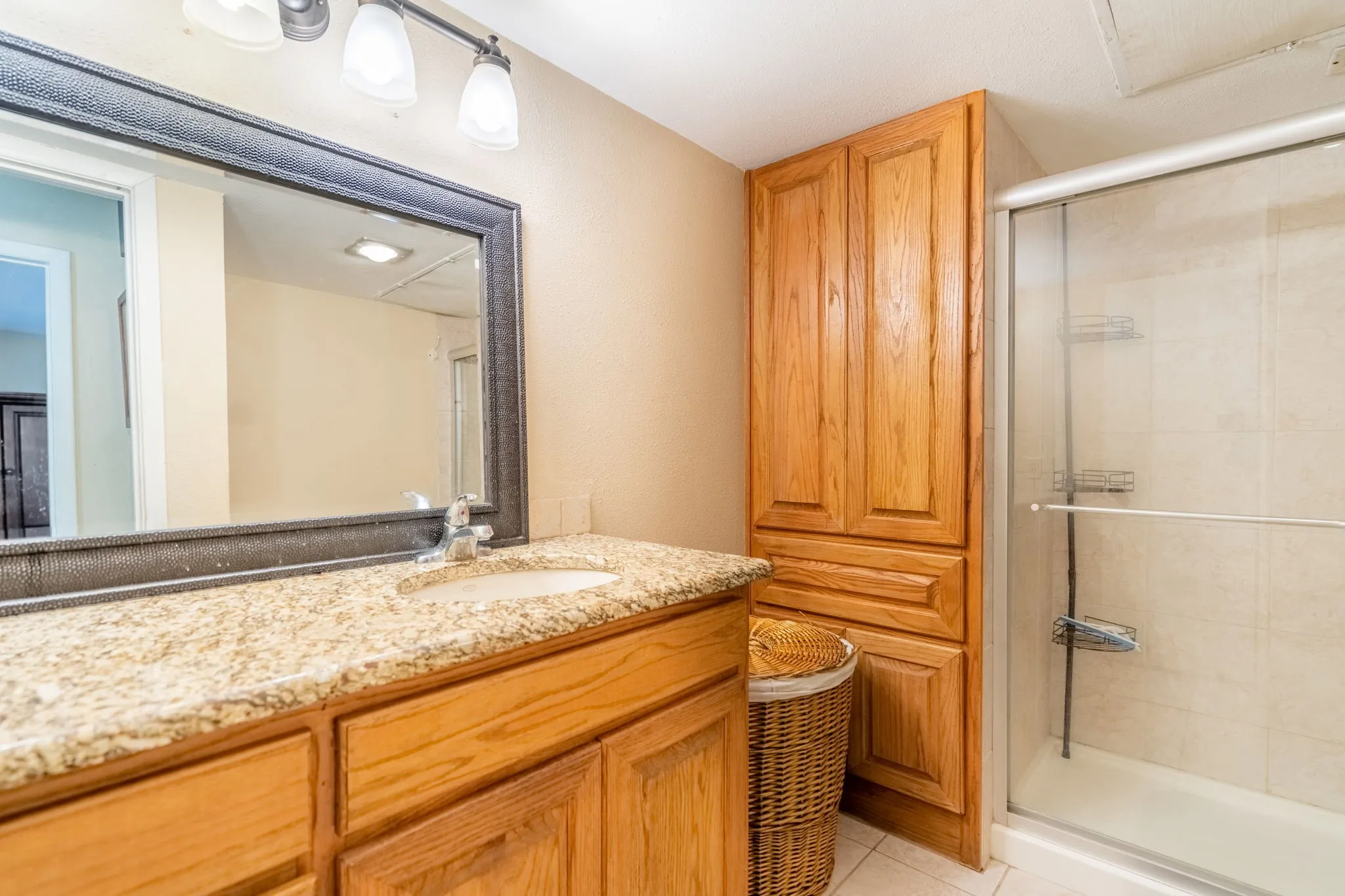 Vanity with a granite-style countertop, undermount sink, and wood-finish cabinetry