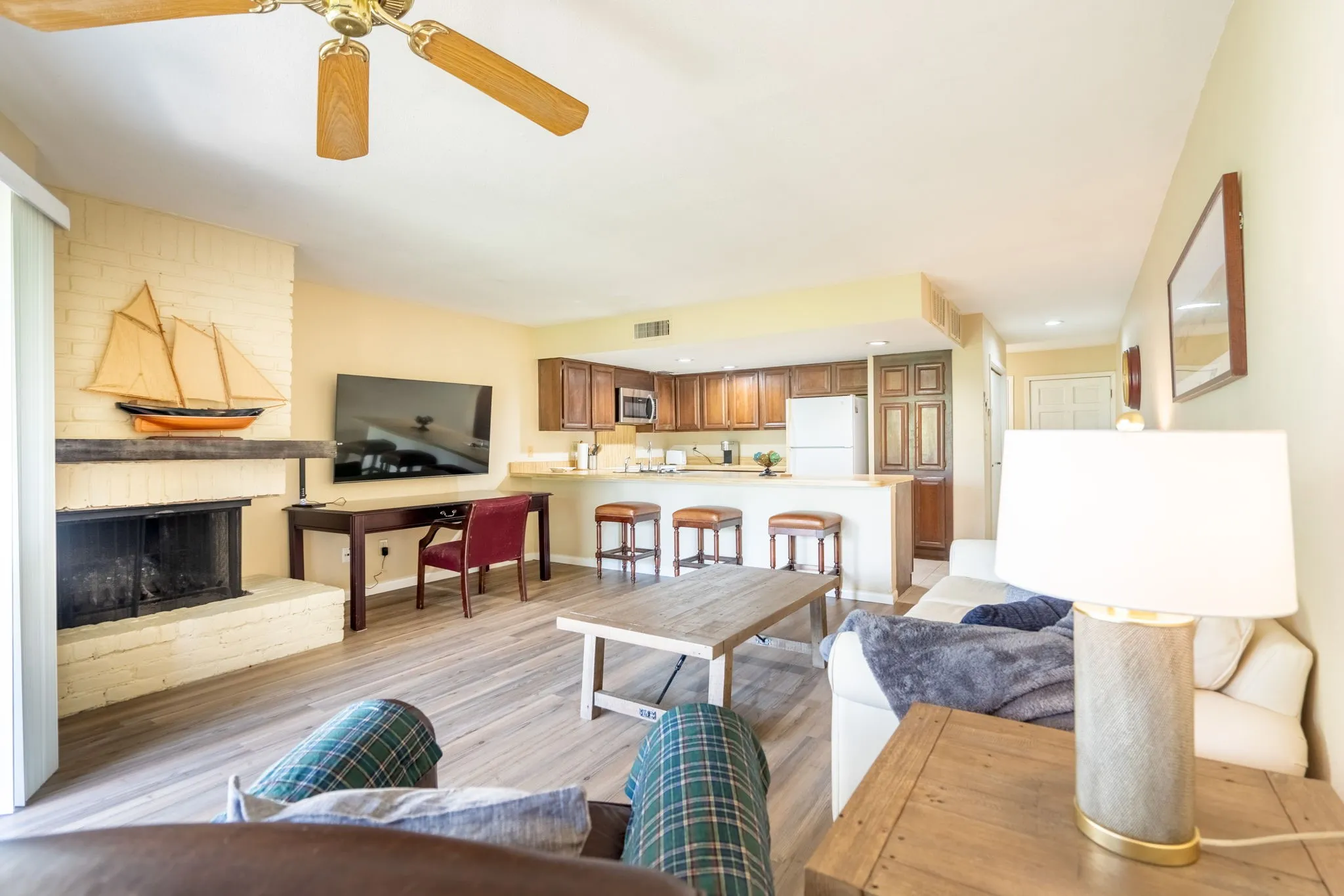 Living area featuring wood-finish flooring, a brick fireplace, and an overhead ceiling fan