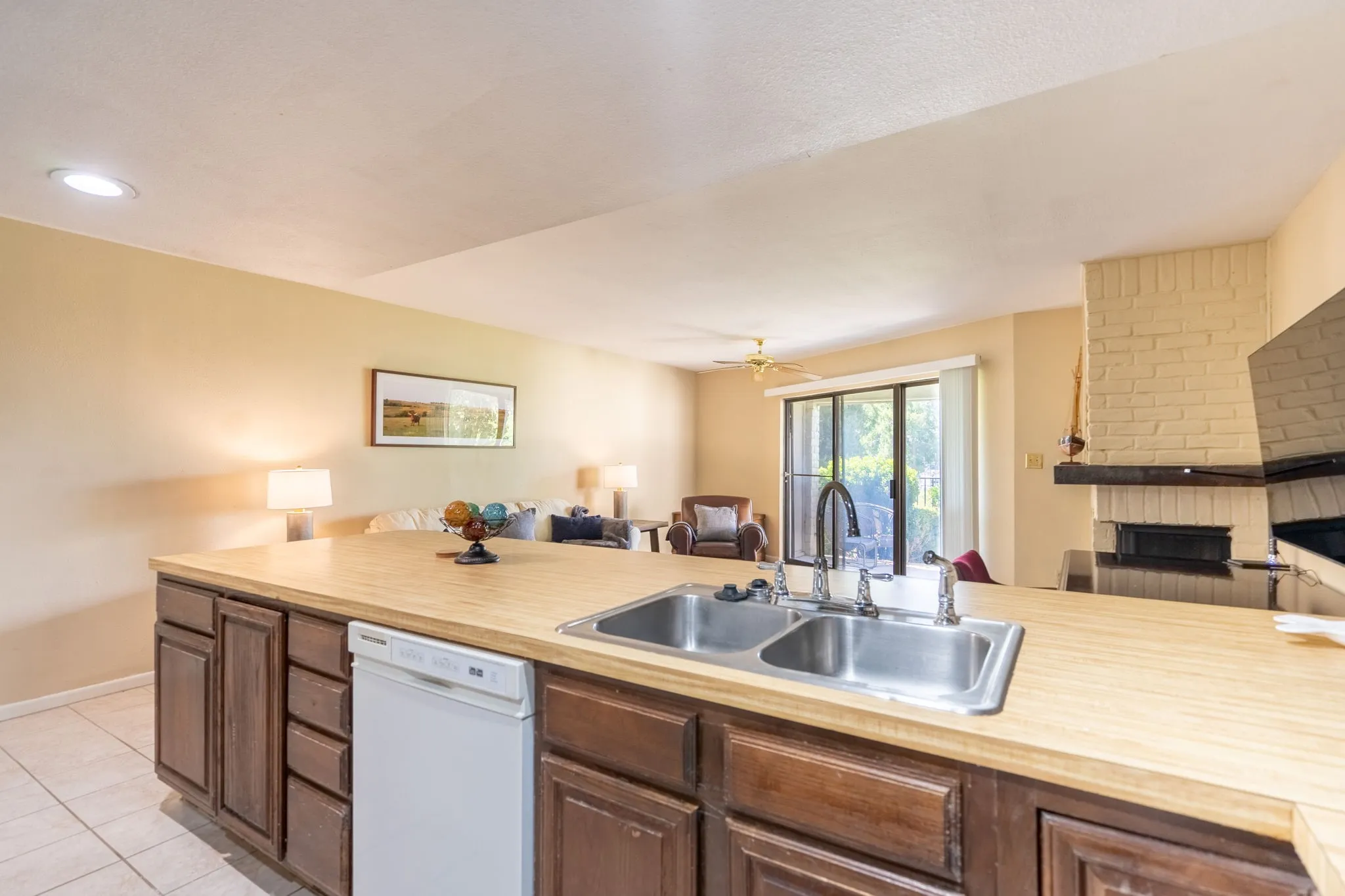 Kitchen with wood-finish countertop, double basin stainless steel sink, and dishwasher