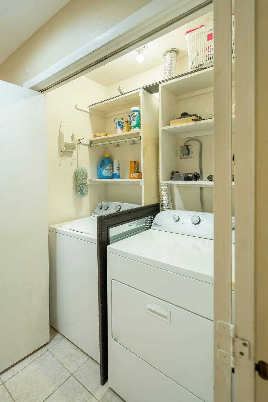 Laundry area featuring built-in shelving, a clothes hanging rod, and tile flooring