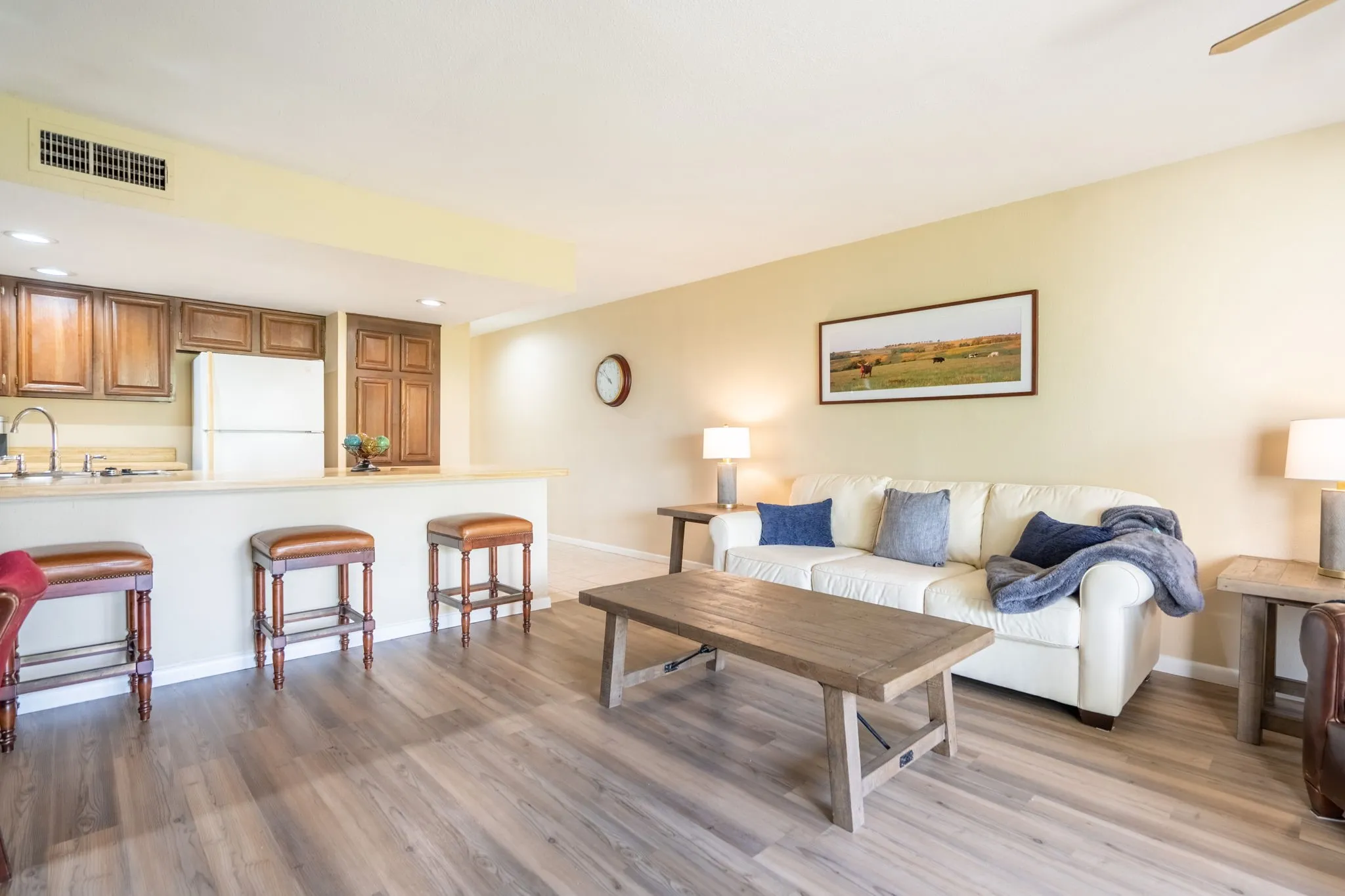 Wood-finish flooring throughout, a kitchen pass-through with a breakfast bar, recessed lighting, ceiling fan, and upper cabinetry