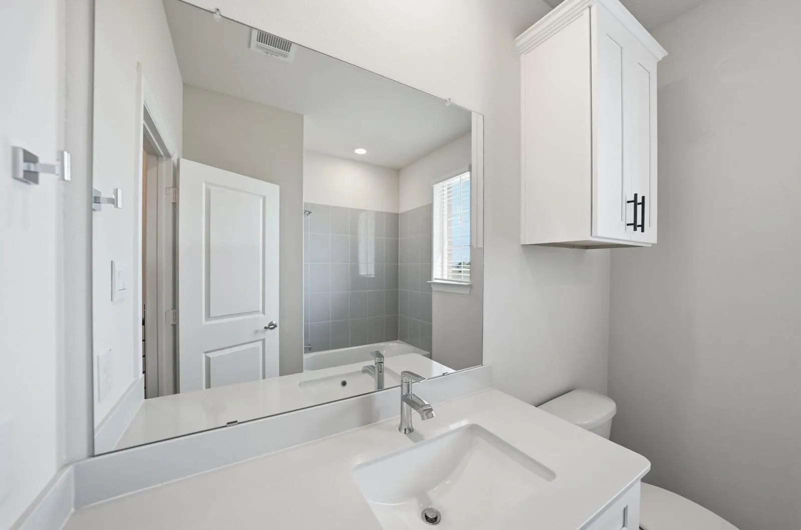 Integrated vanity with an undermount sink, a chrome faucet, and a large wall-mounted mirror