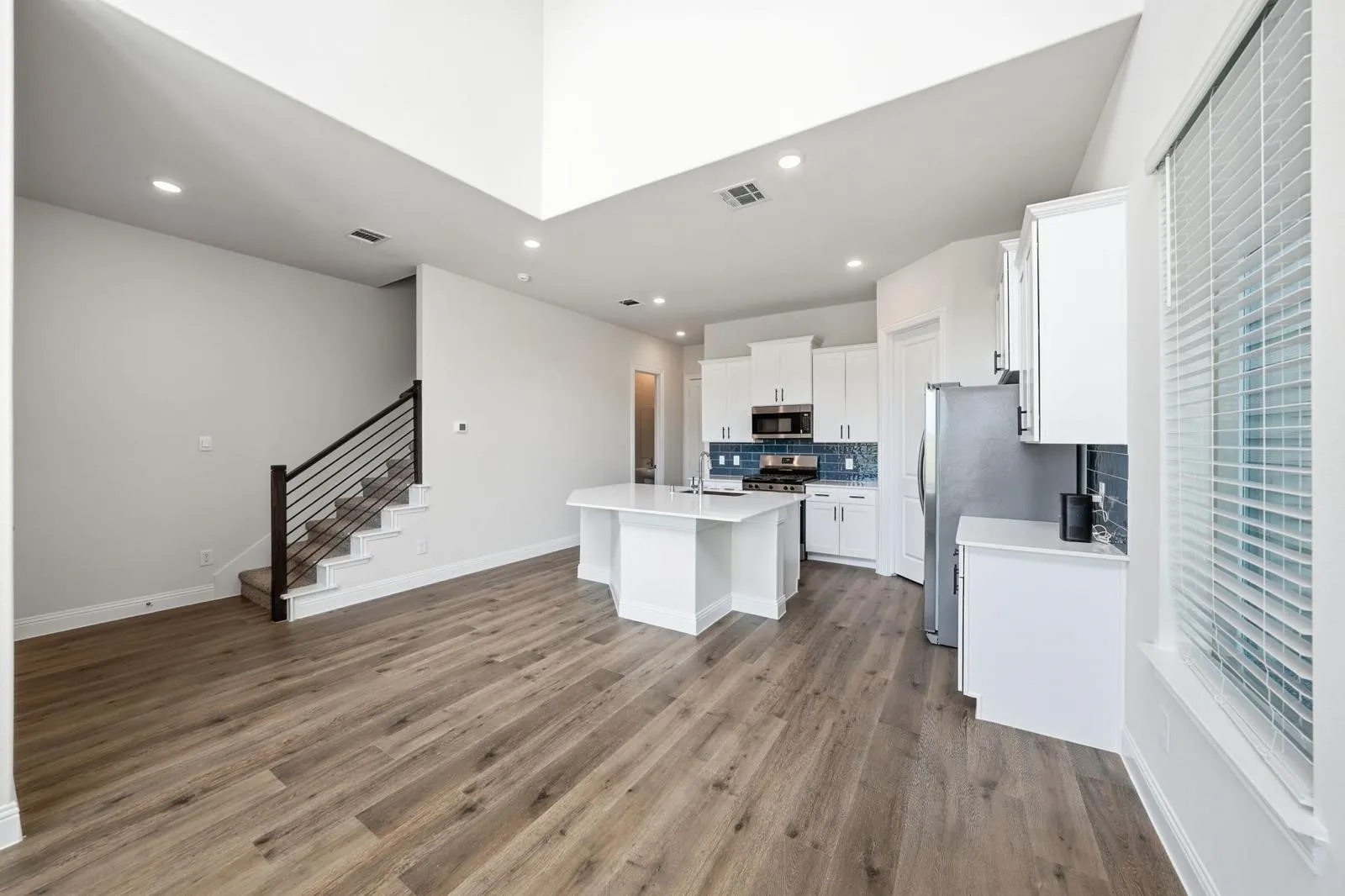 Vaulted ceiling, recessed lighting, wood-finish flooring, kitchen island with built-in cabinetry, and a subway tile backsplash