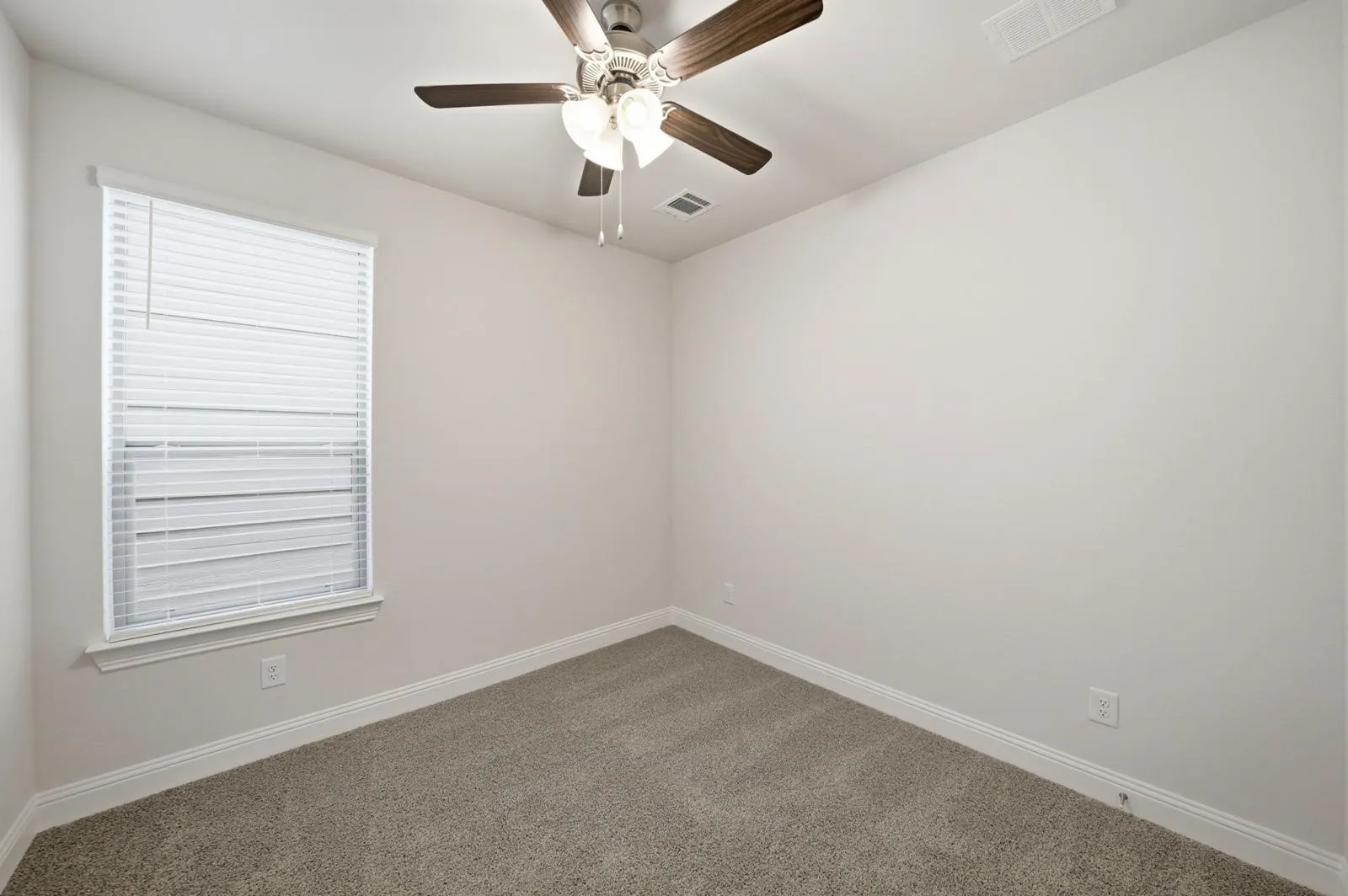 Neutral wall paint, ceiling fan with integrated lighting, window with blinds, and carpeted flooring