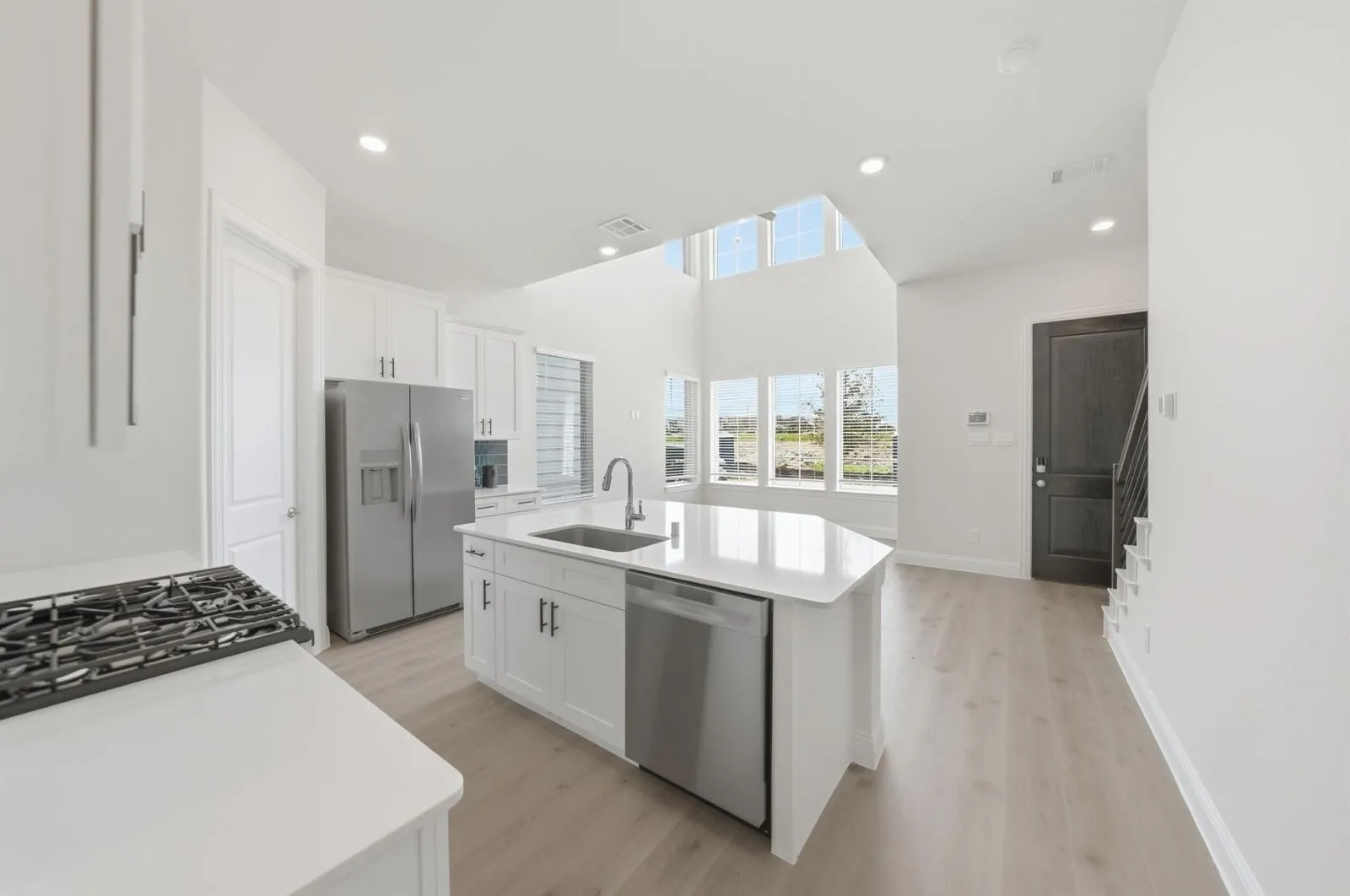 Modern kitchen featuring white cabinetry, stainless steel appliances, a center island with sink, and light wood-finish flooring