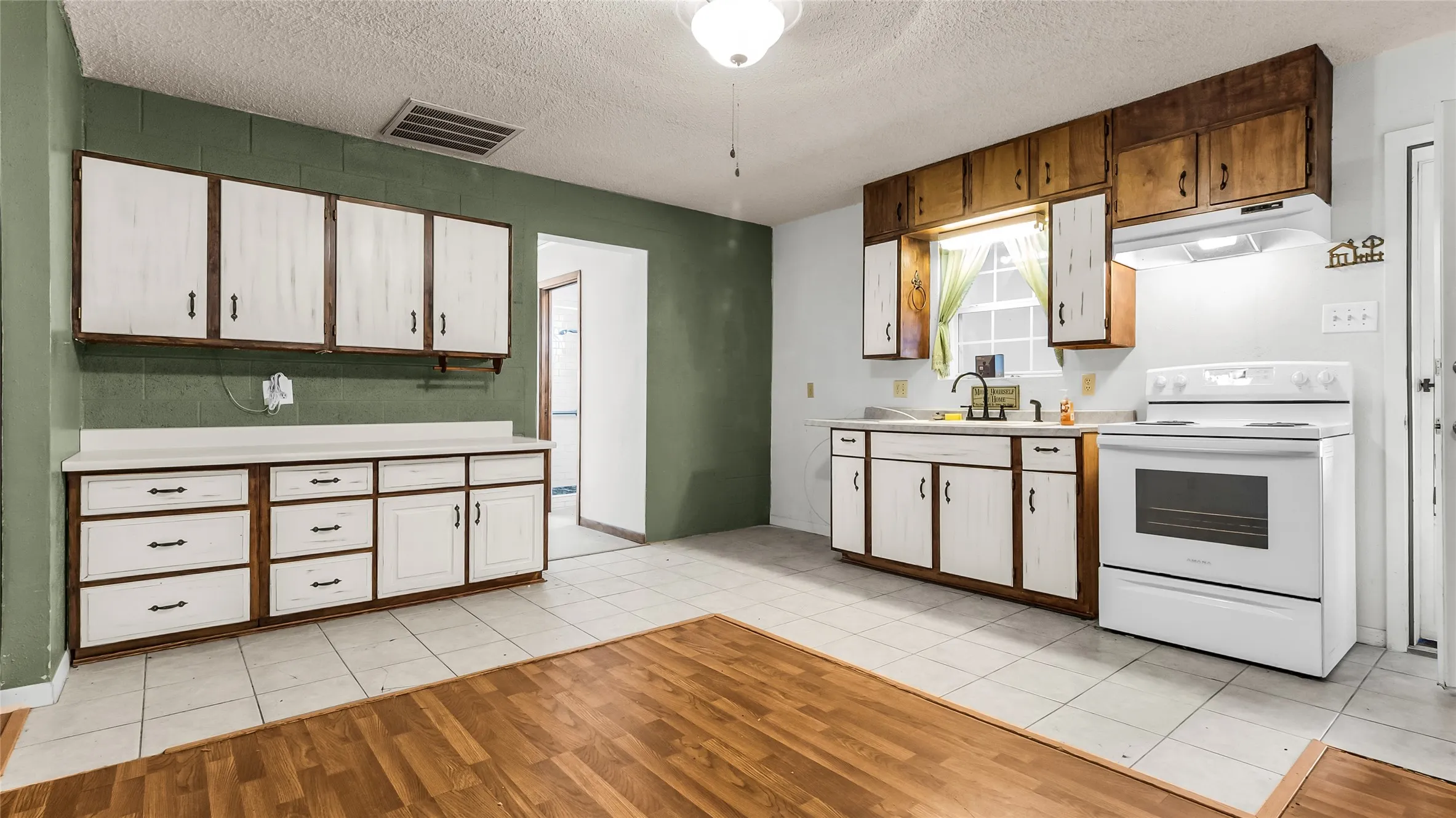 Kitchen featuring white tile flooring, wood-finish flooring, white appliances, and a mix of wood and painted cabinetry