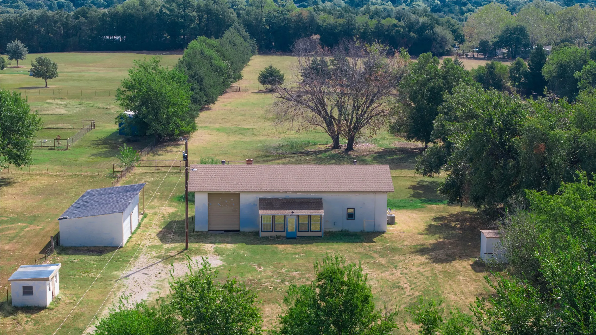 Expansive green space featuring two detached structures, one with a rolling garage door