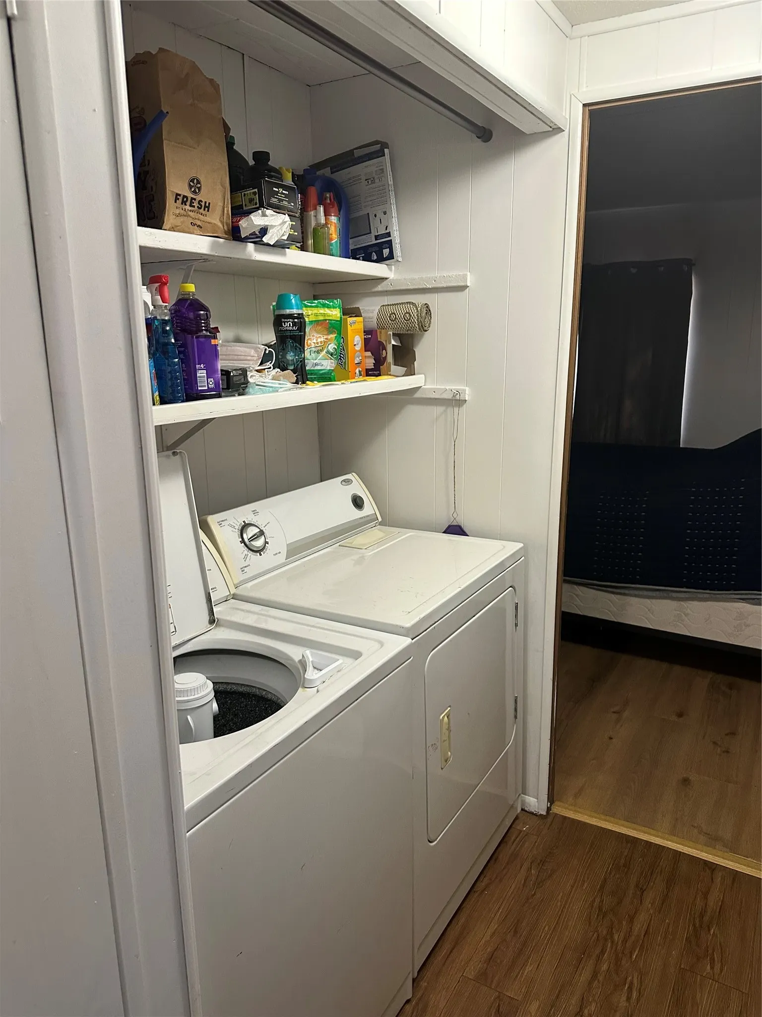 Laundry area with built-in shelving, a clothes rod, and wood-finish flooring