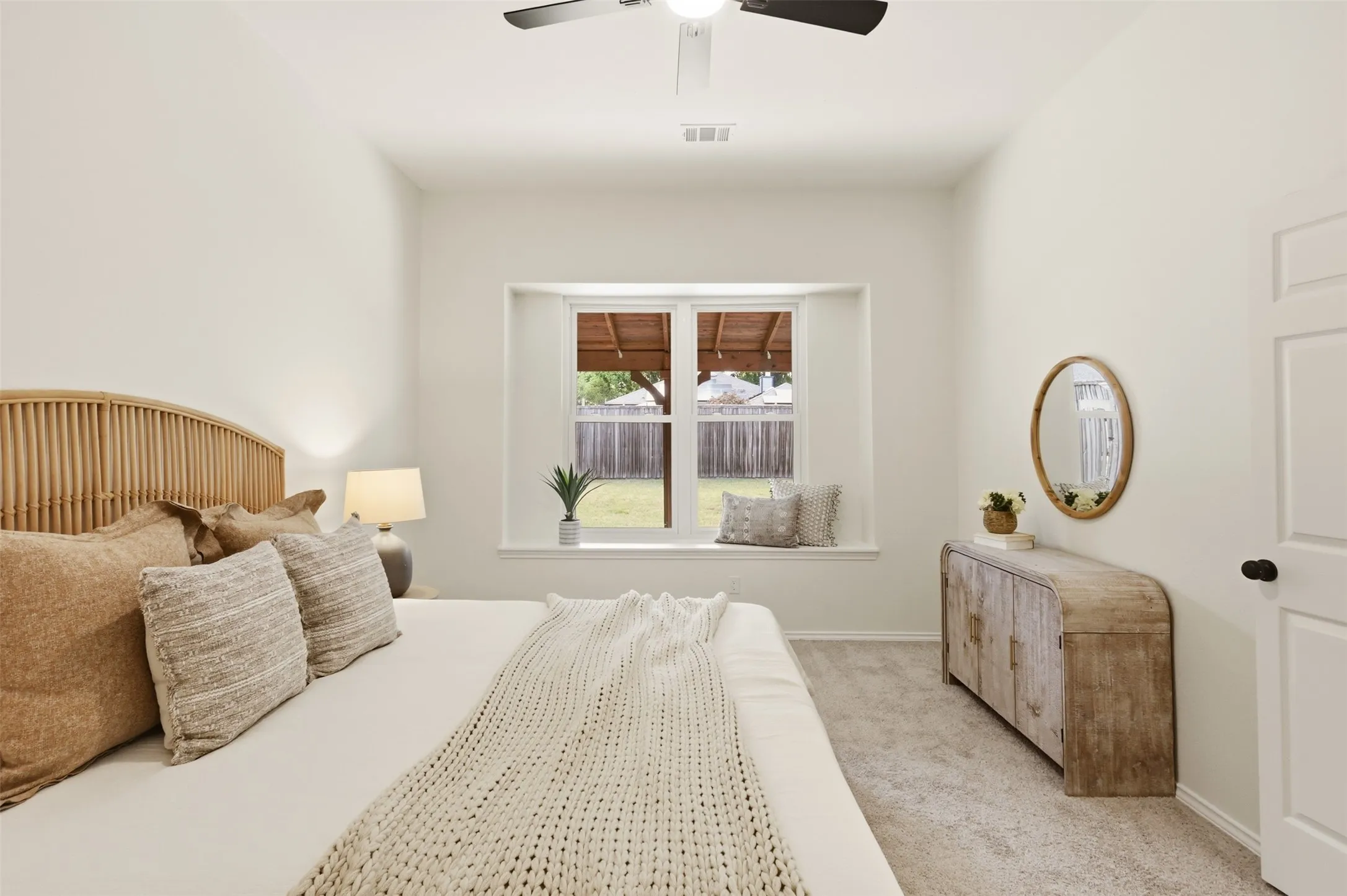 Vaulted ceiling, ceiling fan, window seat, recessed window, and light-colored carpeting