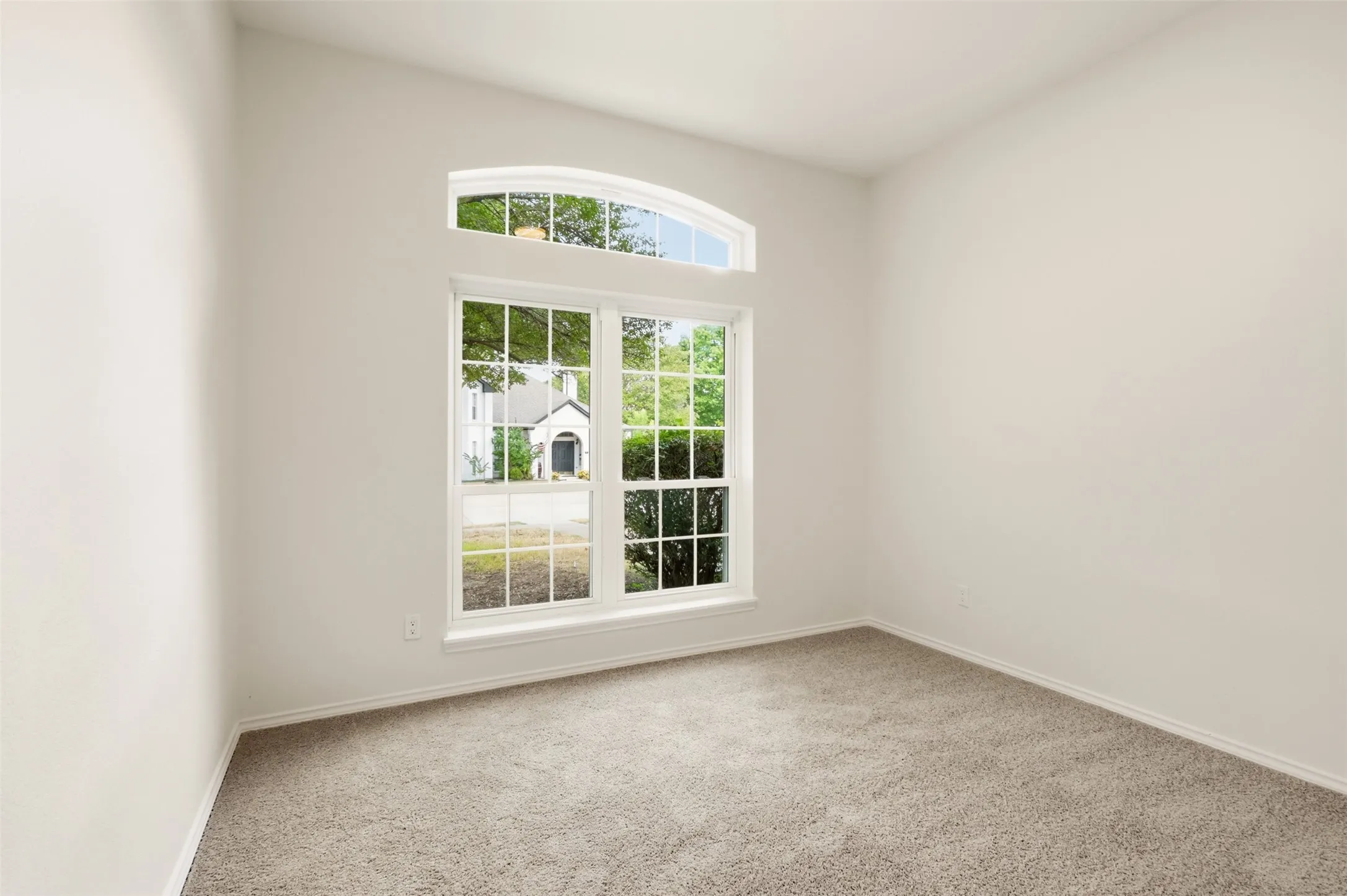 Neutral wall color, arched transom window, picture windows, and gray carpeting