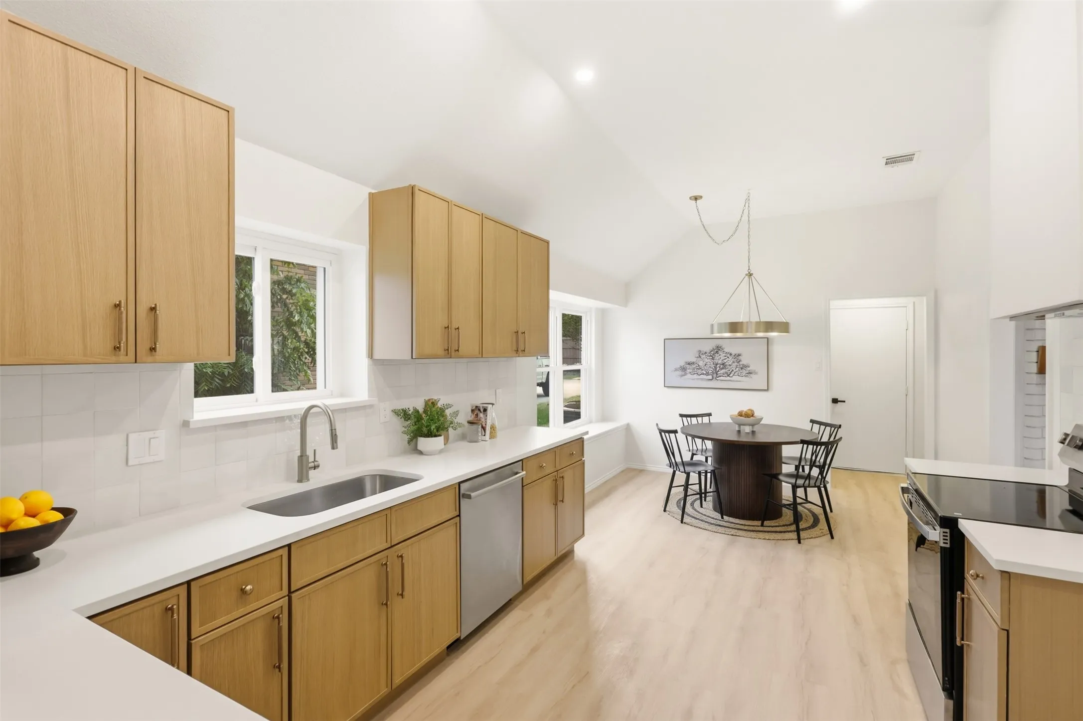 Kitchen featuring wood-finish cabinetry, stainless steel appliances, a stainless steel sink, and light-tone flooring