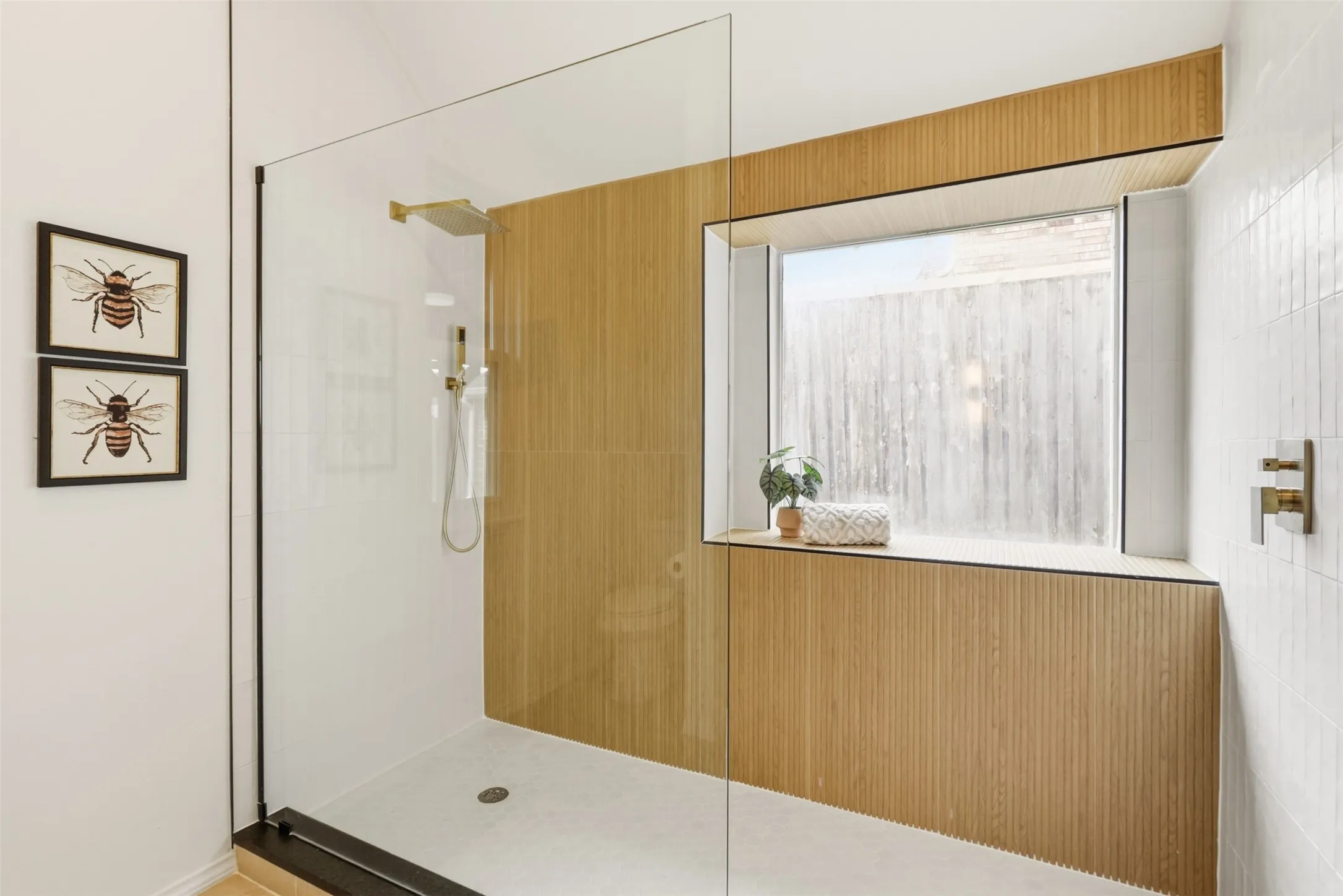 Glass-enclosed shower with a rainfall showerhead, handheld shower fixture, and a built-in window