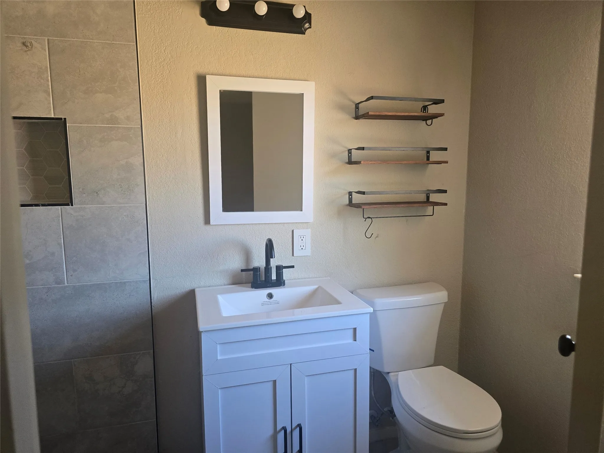 White vanity with integrated sink, black faucet, and white framed mirror