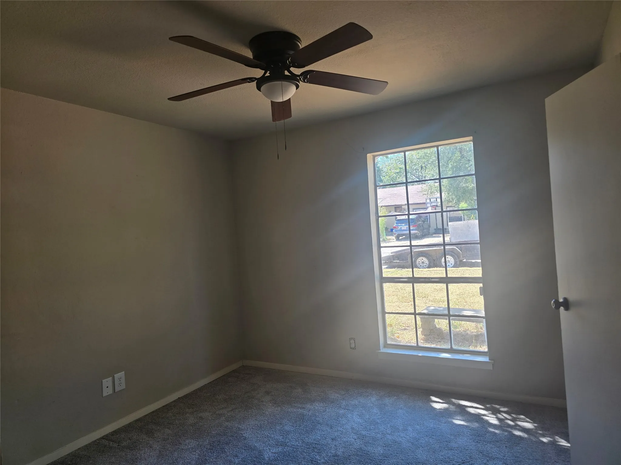 Recessed window with grid pattern, overhead ceiling fan with light fixture, and neutral wall paint