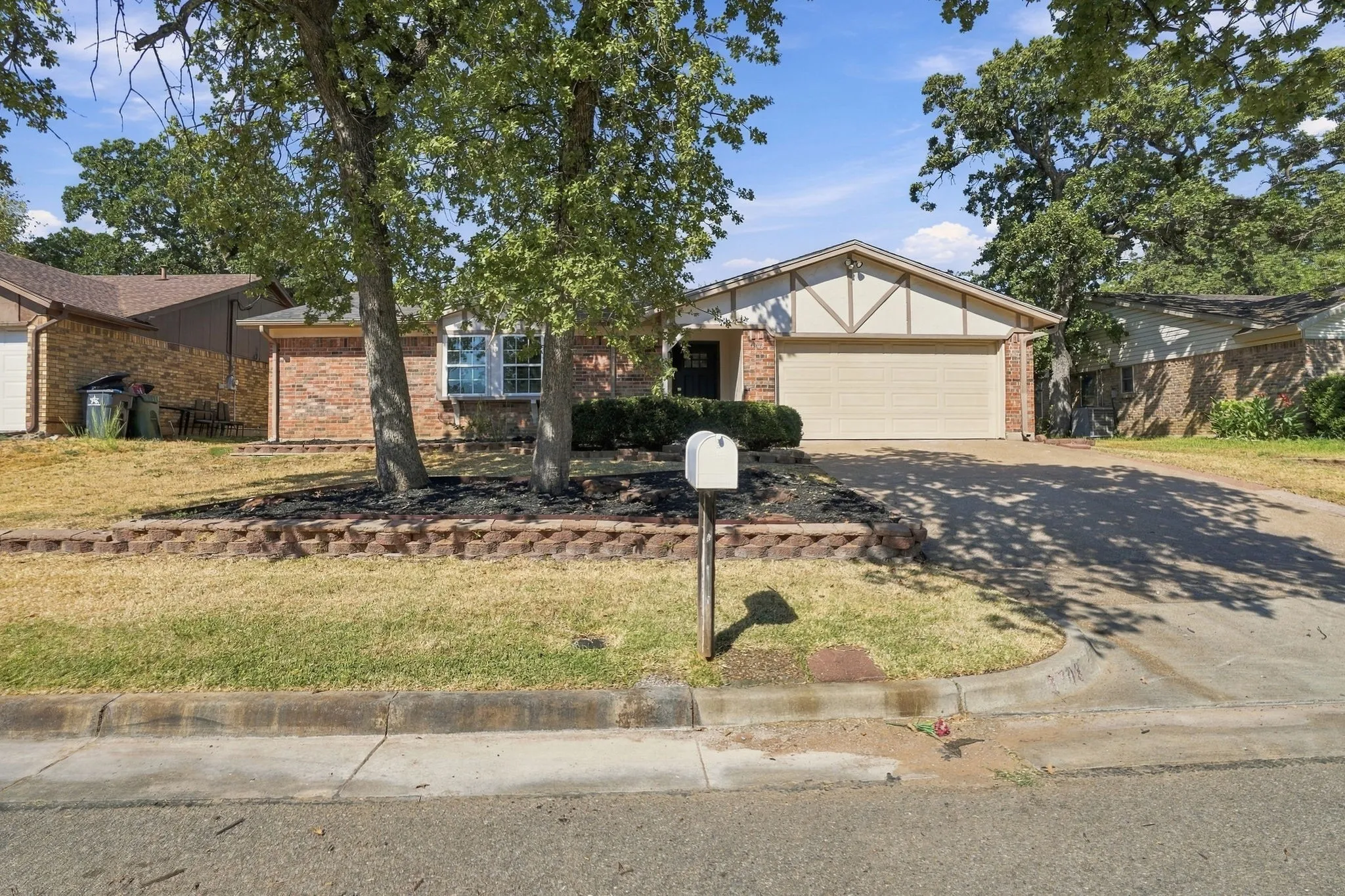 Brick exterior with a gabled roofline, front-facing two-car garage, and a concrete driveway