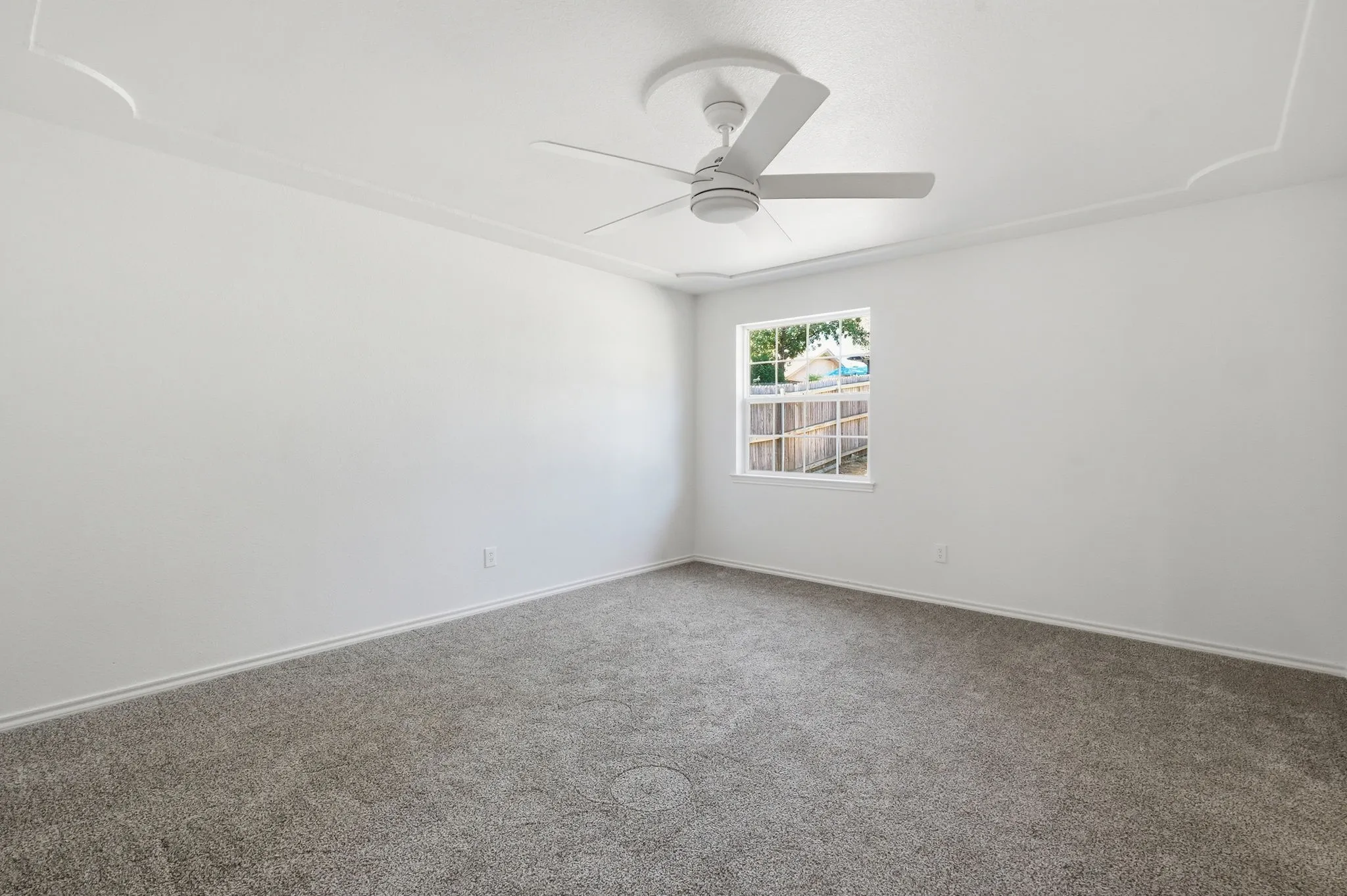 Neutral wall paint, ceiling fan, crown molding, window, and gray carpet
