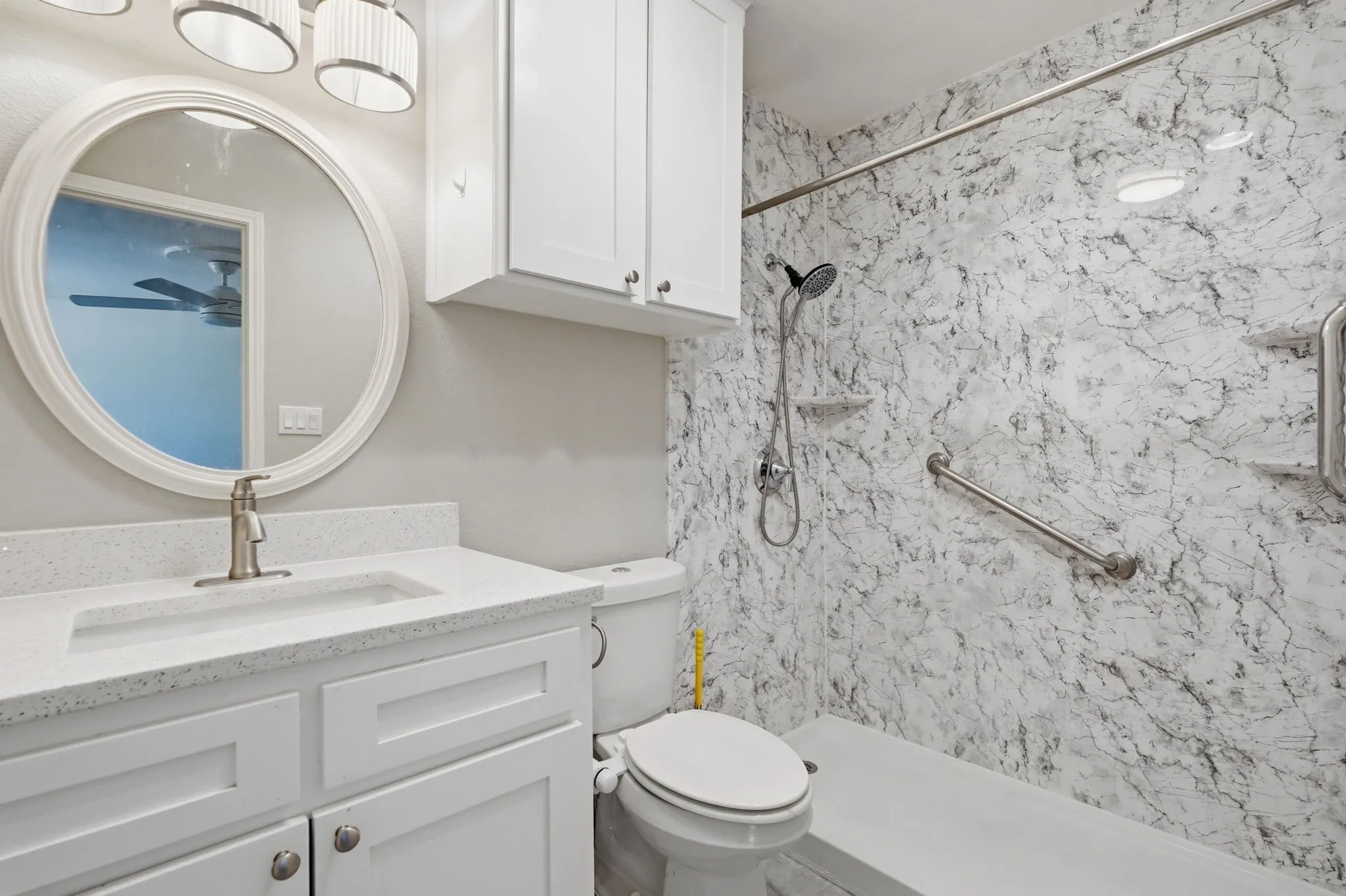 White vanity with an integrated sink and brushed nickel faucet, topped with a white speckled countertop