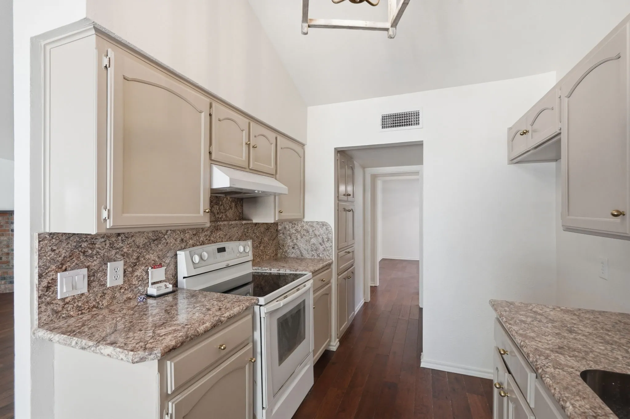 Vaulted ceiling, wood-finish flooring, granite countertops, built-in cabinetry, and integrated electric range