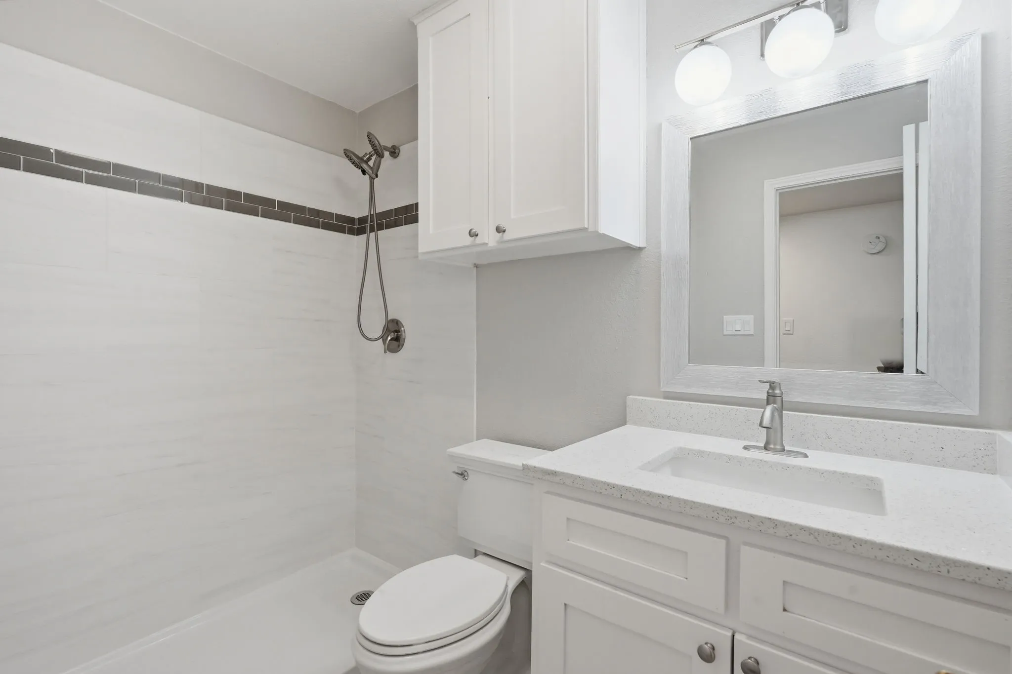 White tile shower with contrasting dark tile accent band