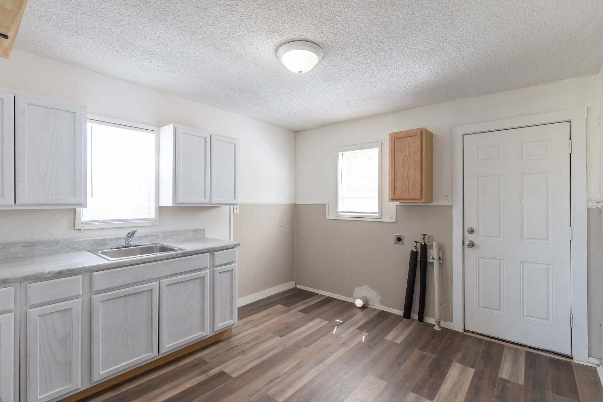 Wood-finish flooring, white cabinetry, integrated sink, and overhead lighting