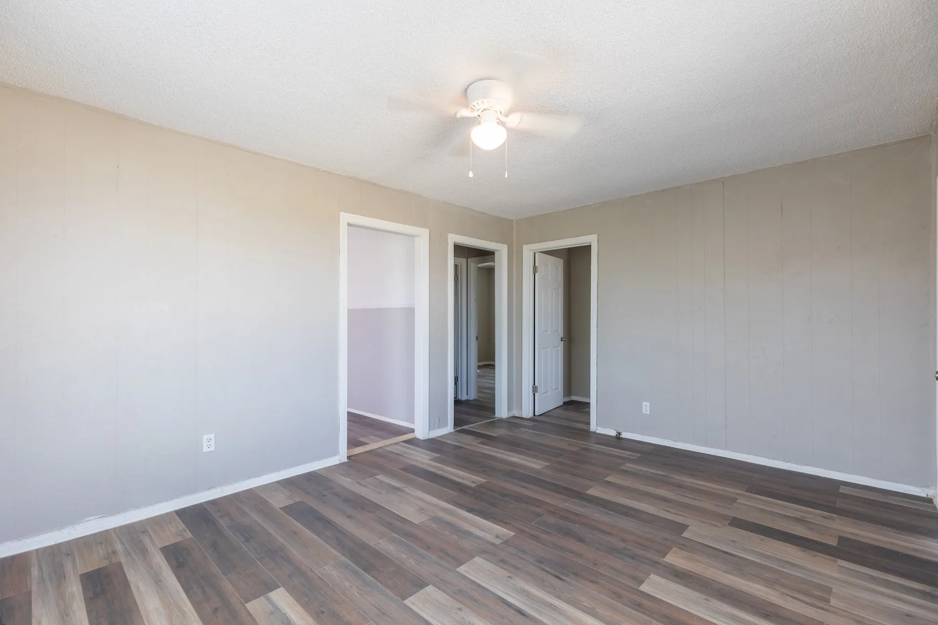 Wood-finish flooring, neutral wall tones, and overhead lighting with a ceiling fan